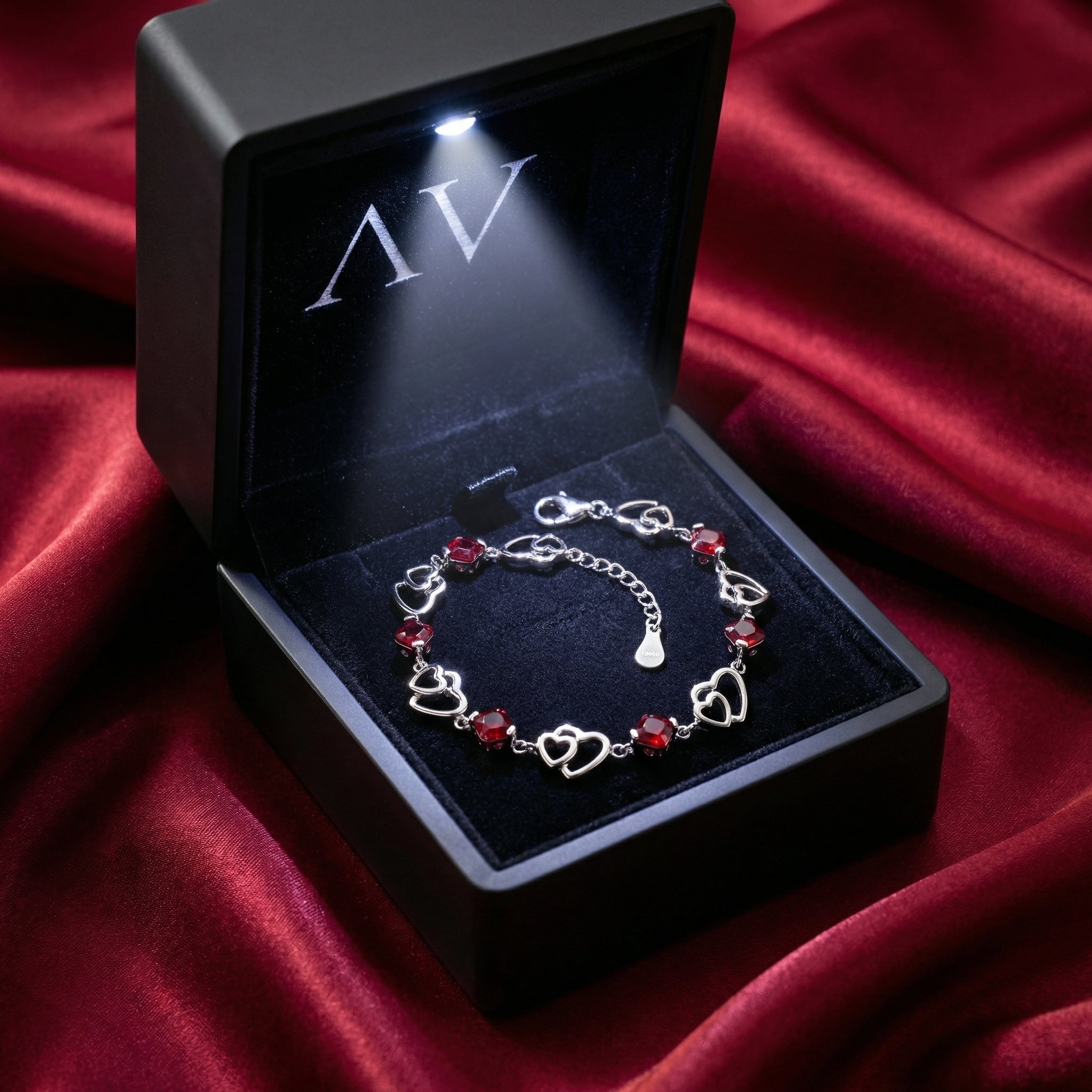 Sterling silver heart bracelet with red simulated rubies in a premium lighted black jewelry box.