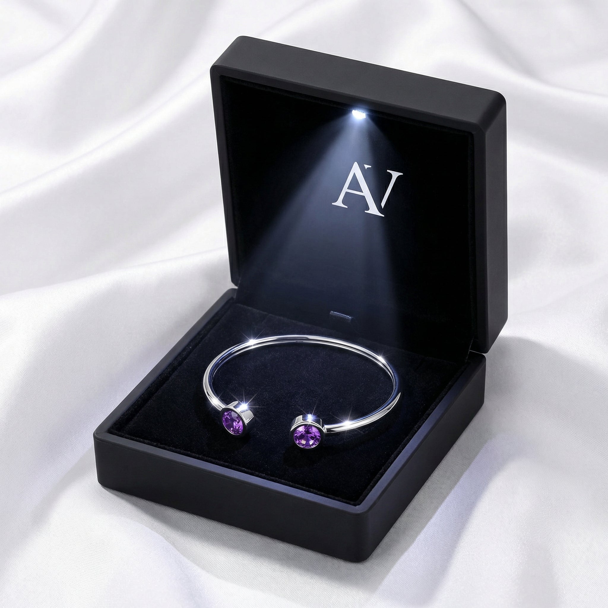 Silver stainless steel Liora amethyst bracelet in a black LED-lit jewelry box on white fabric.