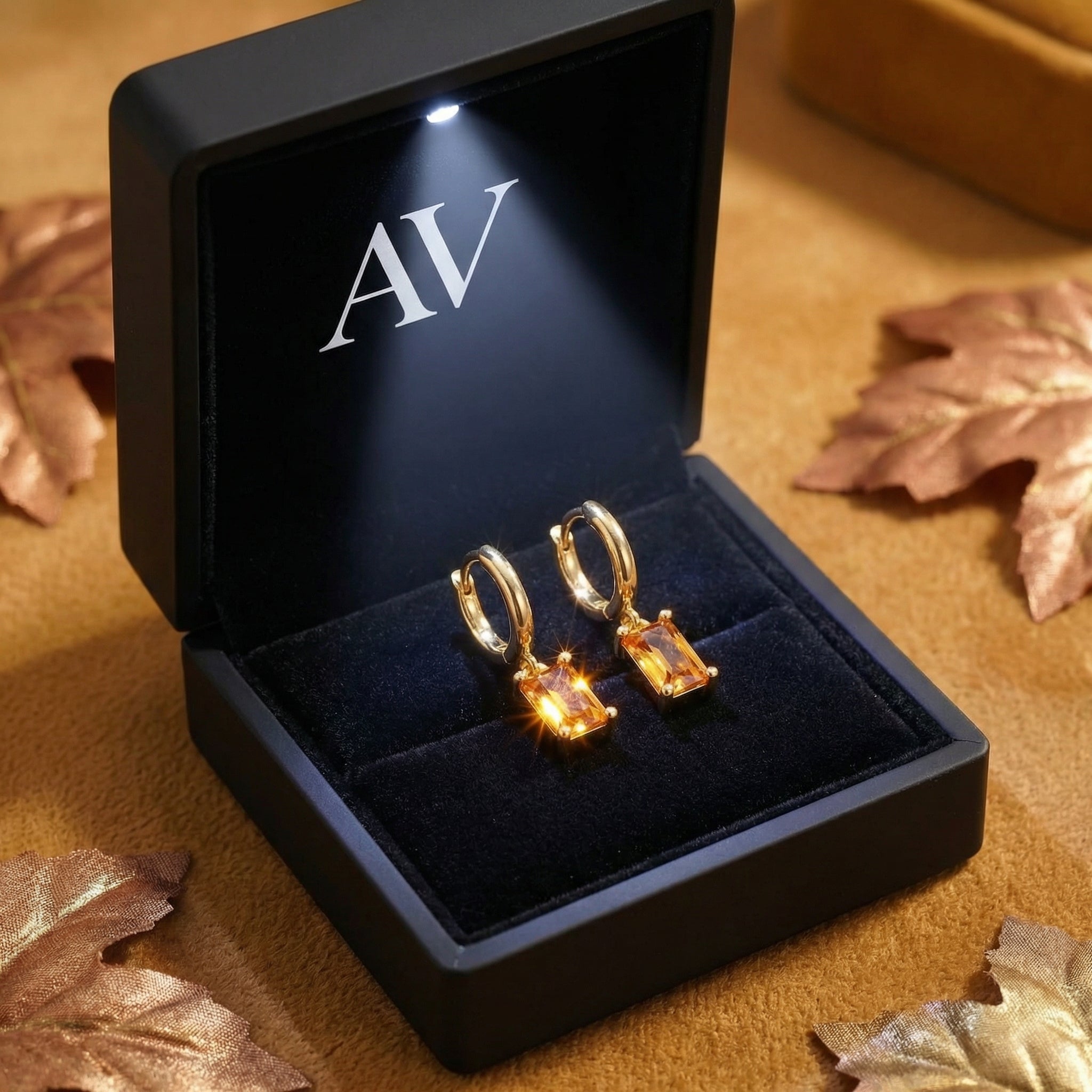 Gold vermeil honey topaz drop earrings presented in a black LED-lit jewelry box with autumn leaves.
