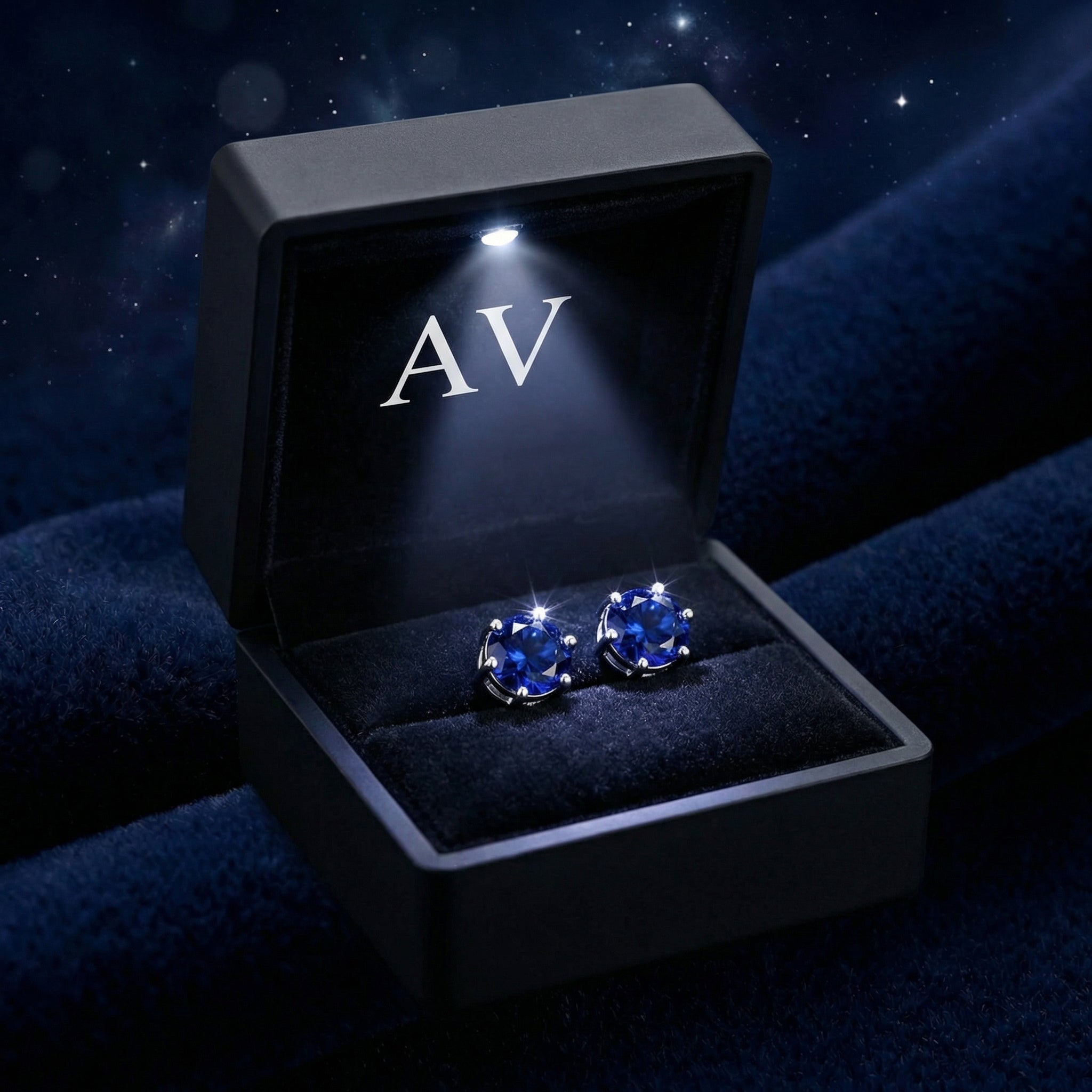 Round blue simulated sapphire earrings in a black LED-lit presentation gift box on blue velvet.