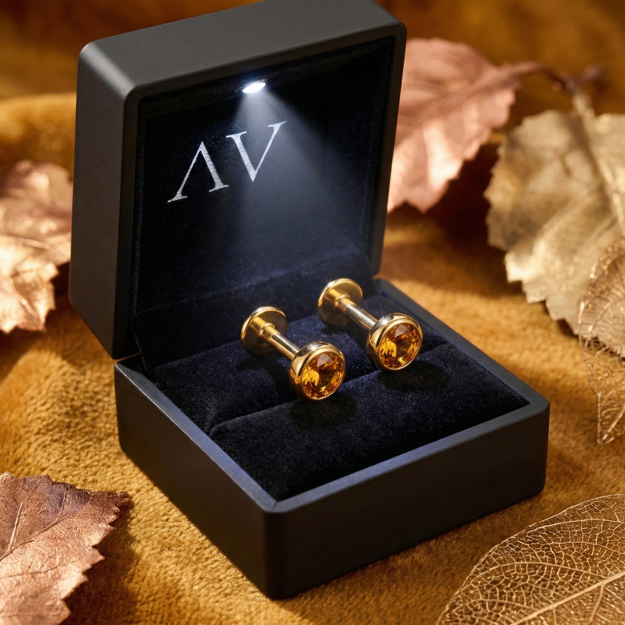 Gold vermeil honey topaz stud earrings displayed in a black LED-lit jewelry box on a velvet surface.