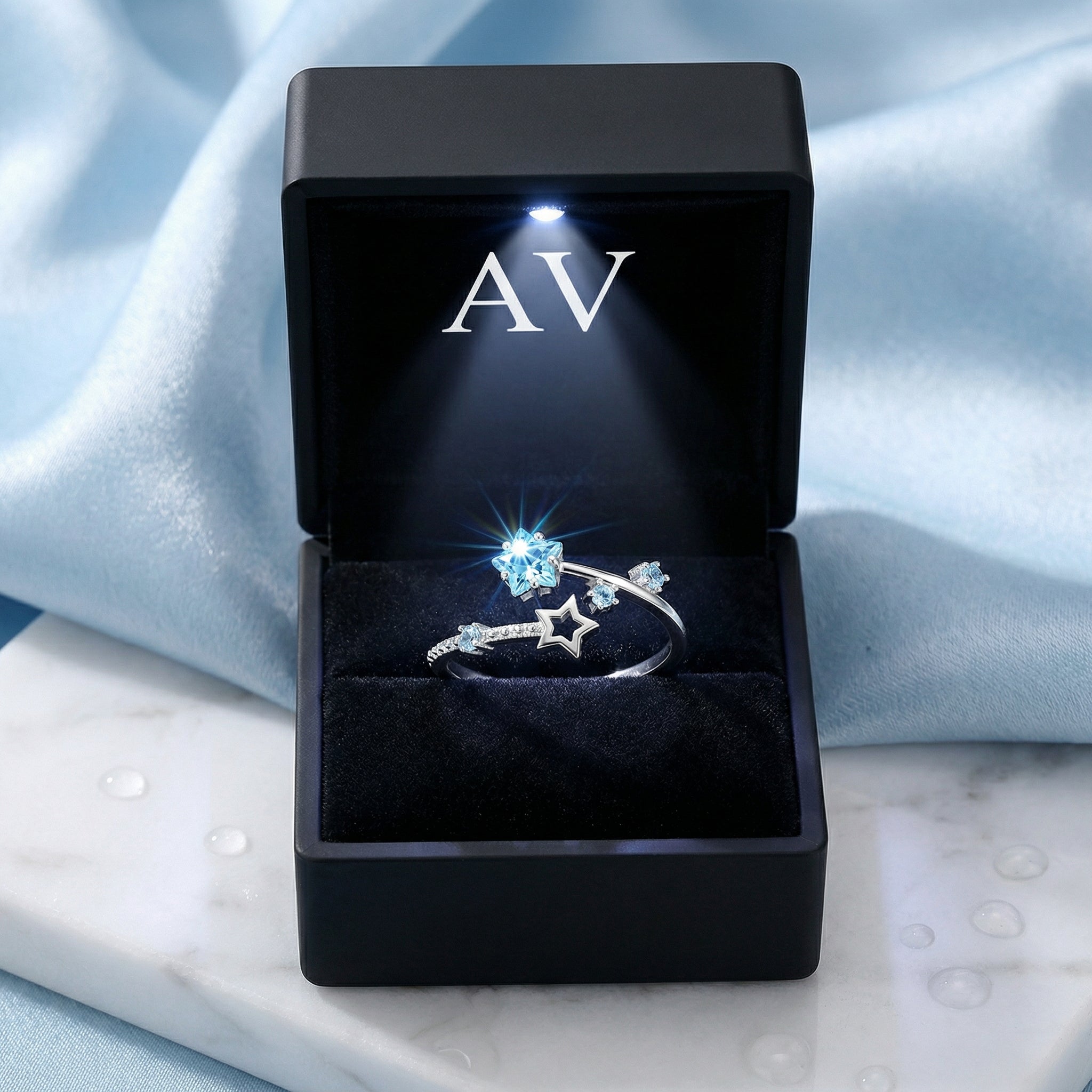 Stella bypass ring with simulated aquamarine stars presented in a black LED-lit jewelry gift box.
