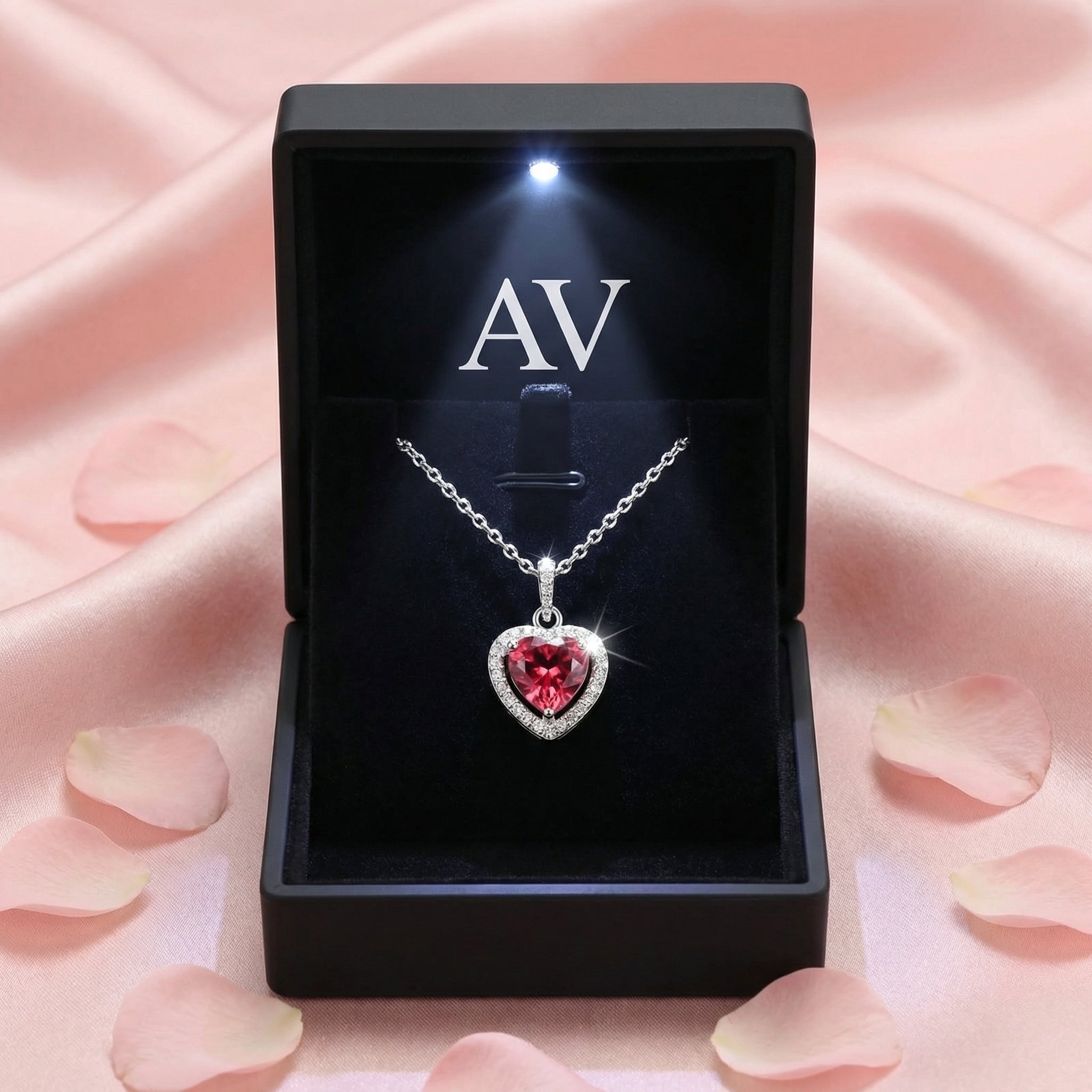 Sterling silver Valentis Heart necklace displayed in a black LED-lit gift box on a pink petal background.