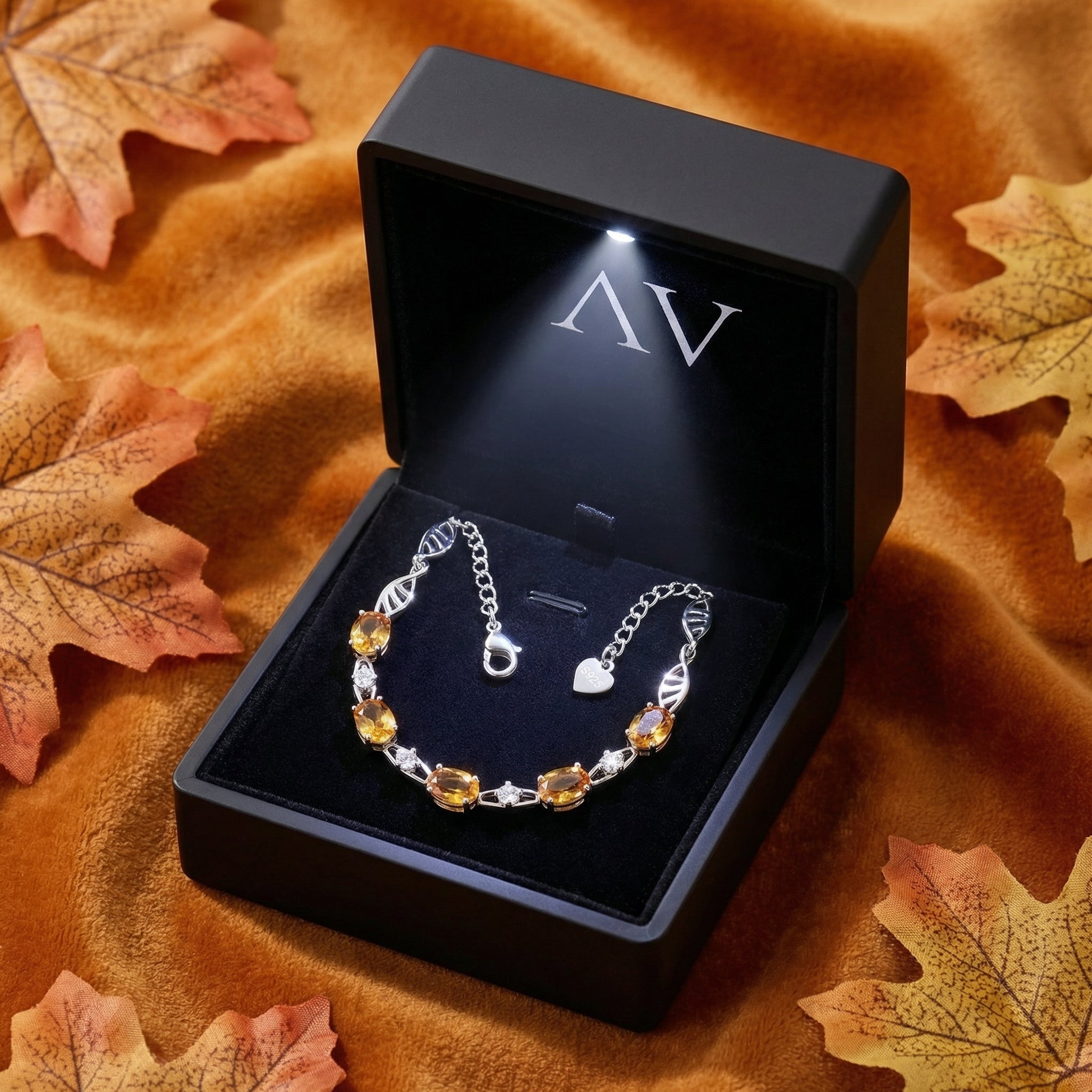 Silver simulated topaz wave bracelet inside a black LED-lighted jewelry gift box surrounded by autumn leaves.