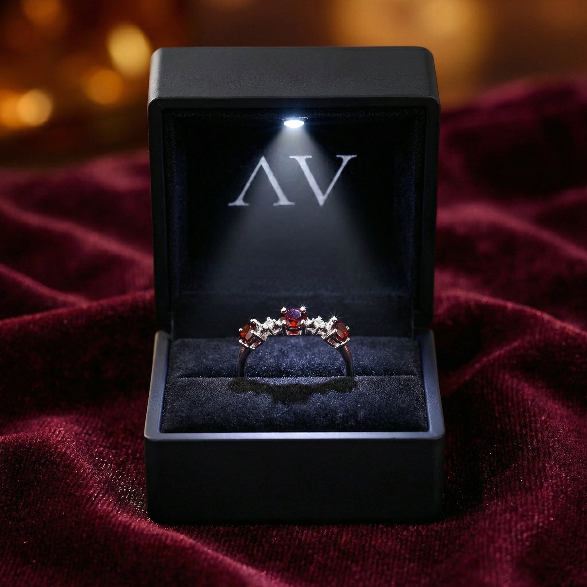 S925 sterling silver bypass ring with round red garnets in a black LED-lit jewelry box.