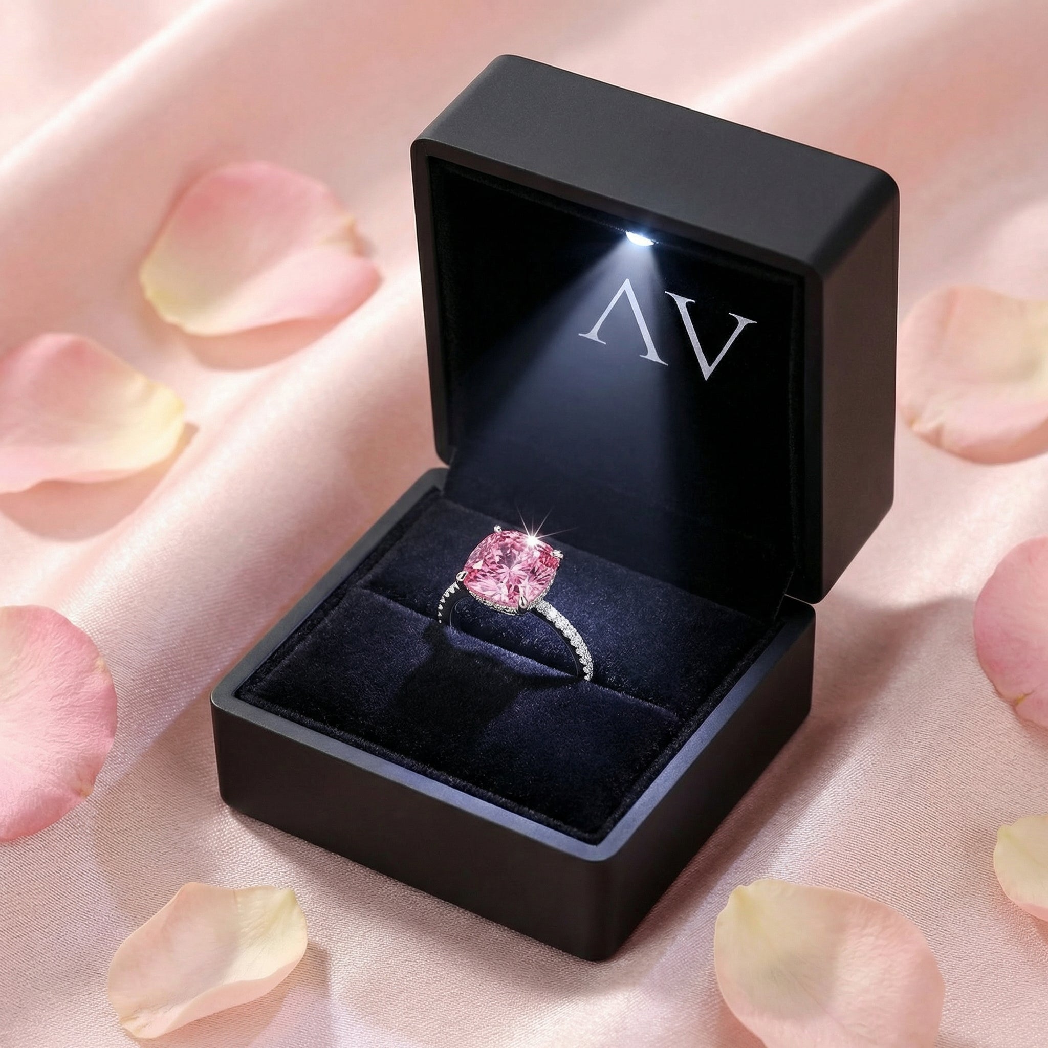 Cushion-cut pink tourmaline ring presented in a premium black LED-lit jewelry box with rose petals.