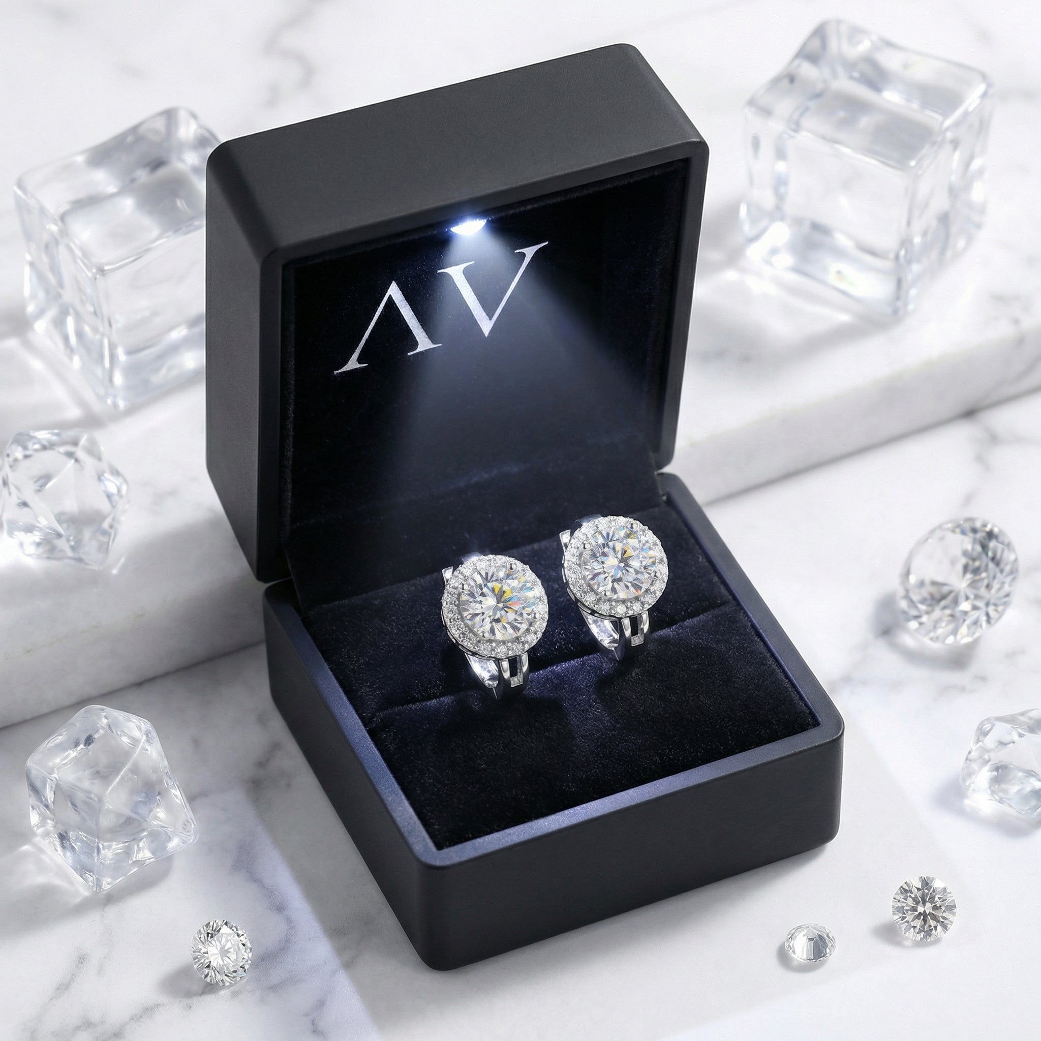 Moissanite halo earrings presented in a black LED-lit gift box with AV branding on a marble surface.