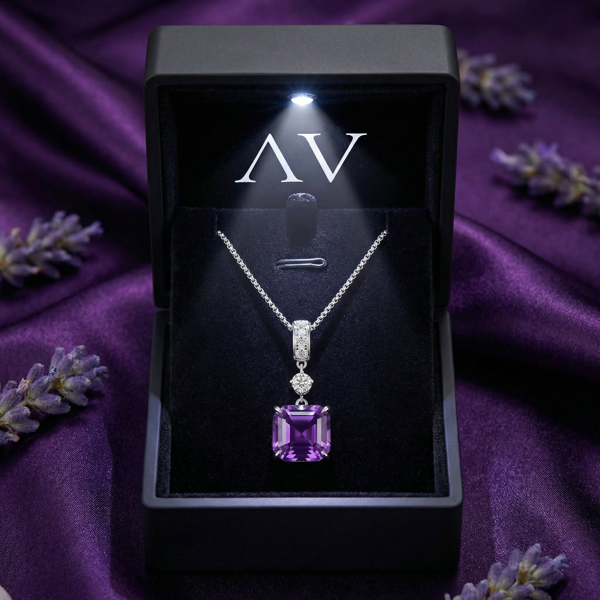 Square cut amethyst pendant necklace in a black LED-lit gift box on purple silk.