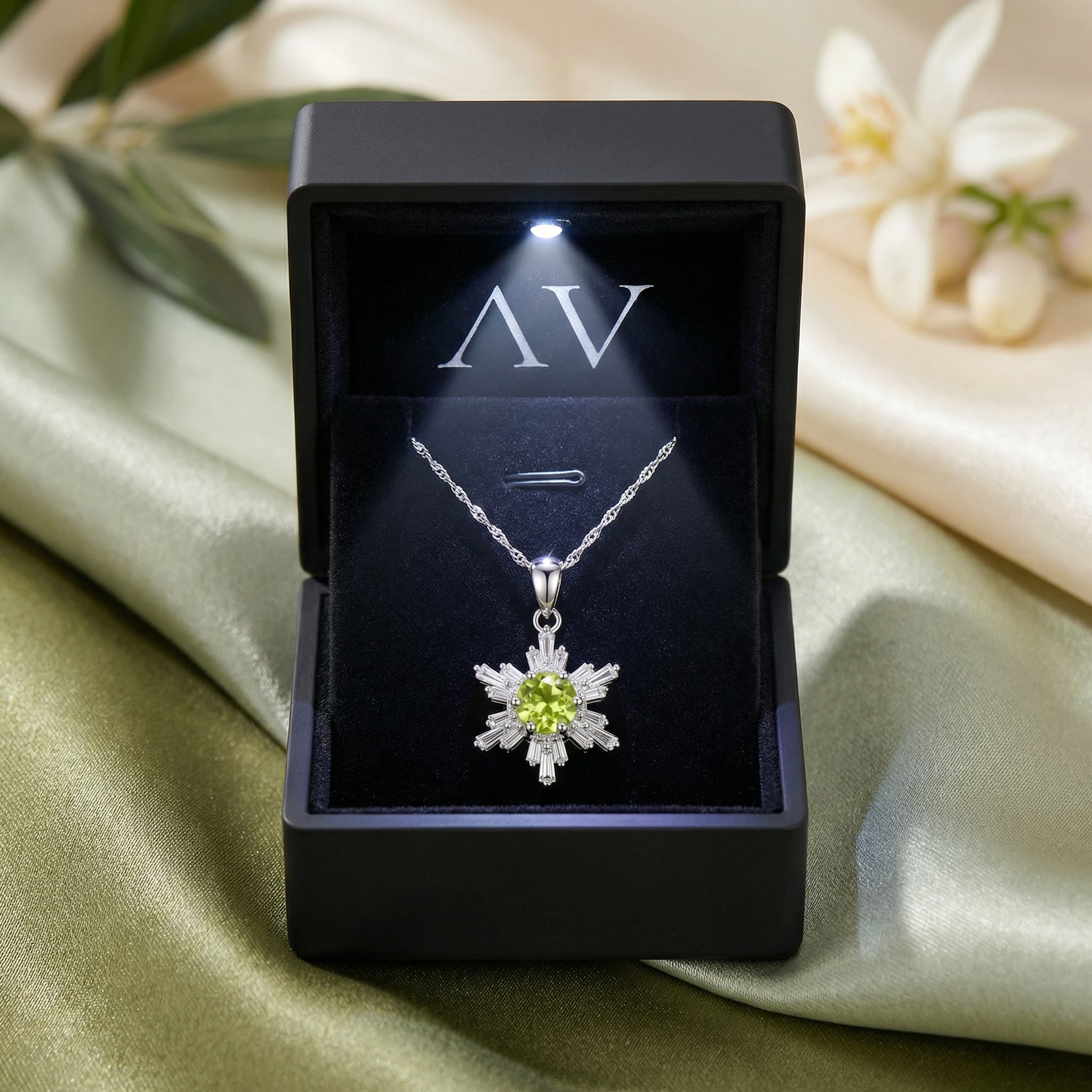 Natural peridot snowflake pendant in a black LED-lit jewelry gift box with AV branding.