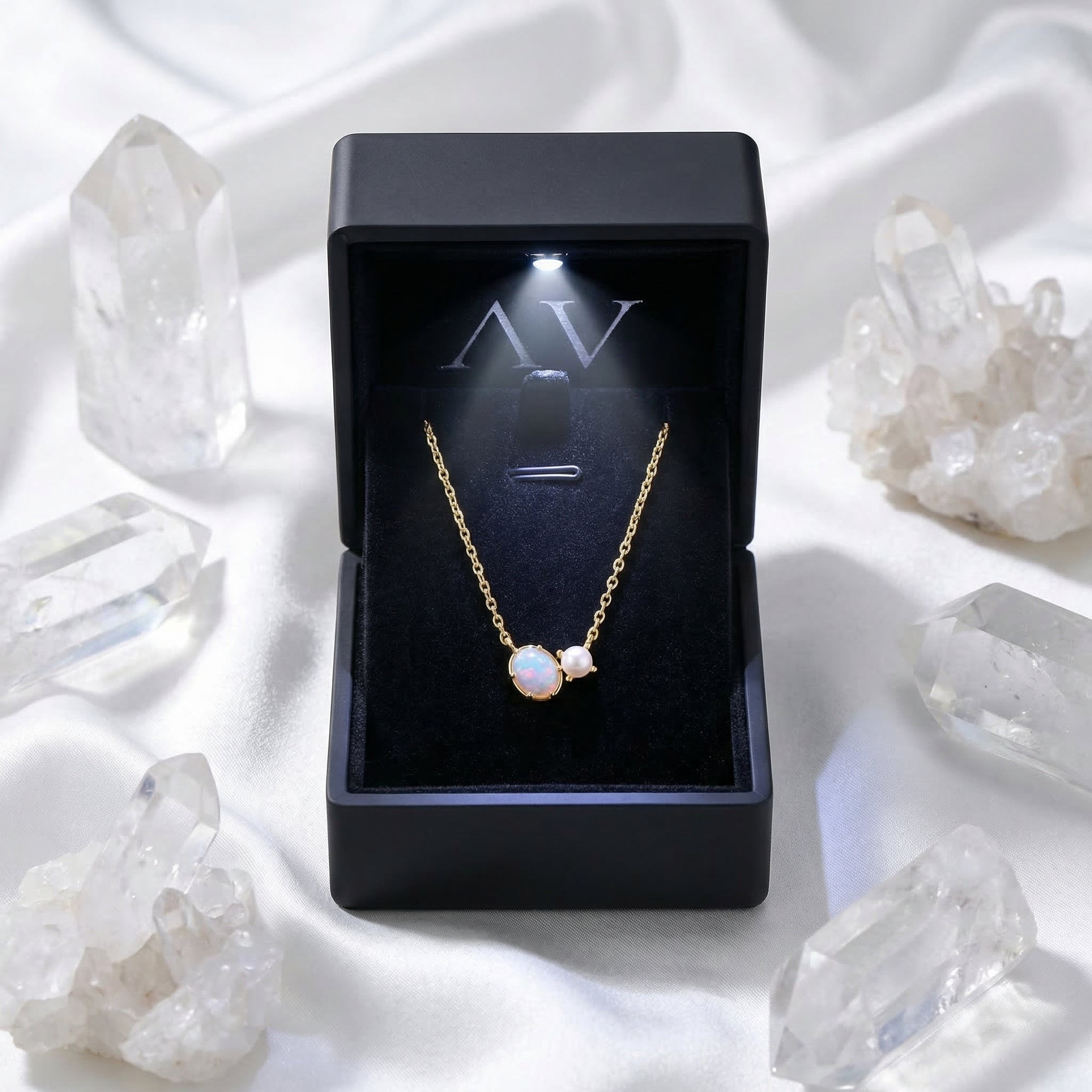 Gold oval white opal necklace inside a black LED-lit jewelry box with quartz crystal props.