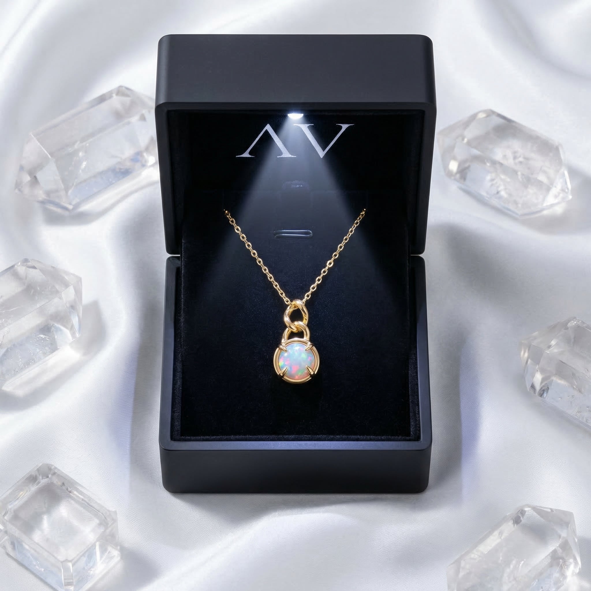 Gold-tone round cut white opal necklace presented in a lighted black gift box on white silk.