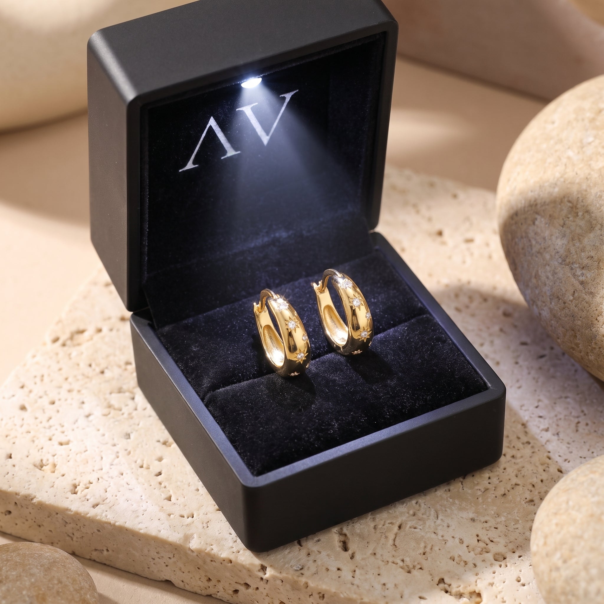 Gold Stellaura starburst earrings with simulated diamonds inside a black LED-lit presentation gift box.