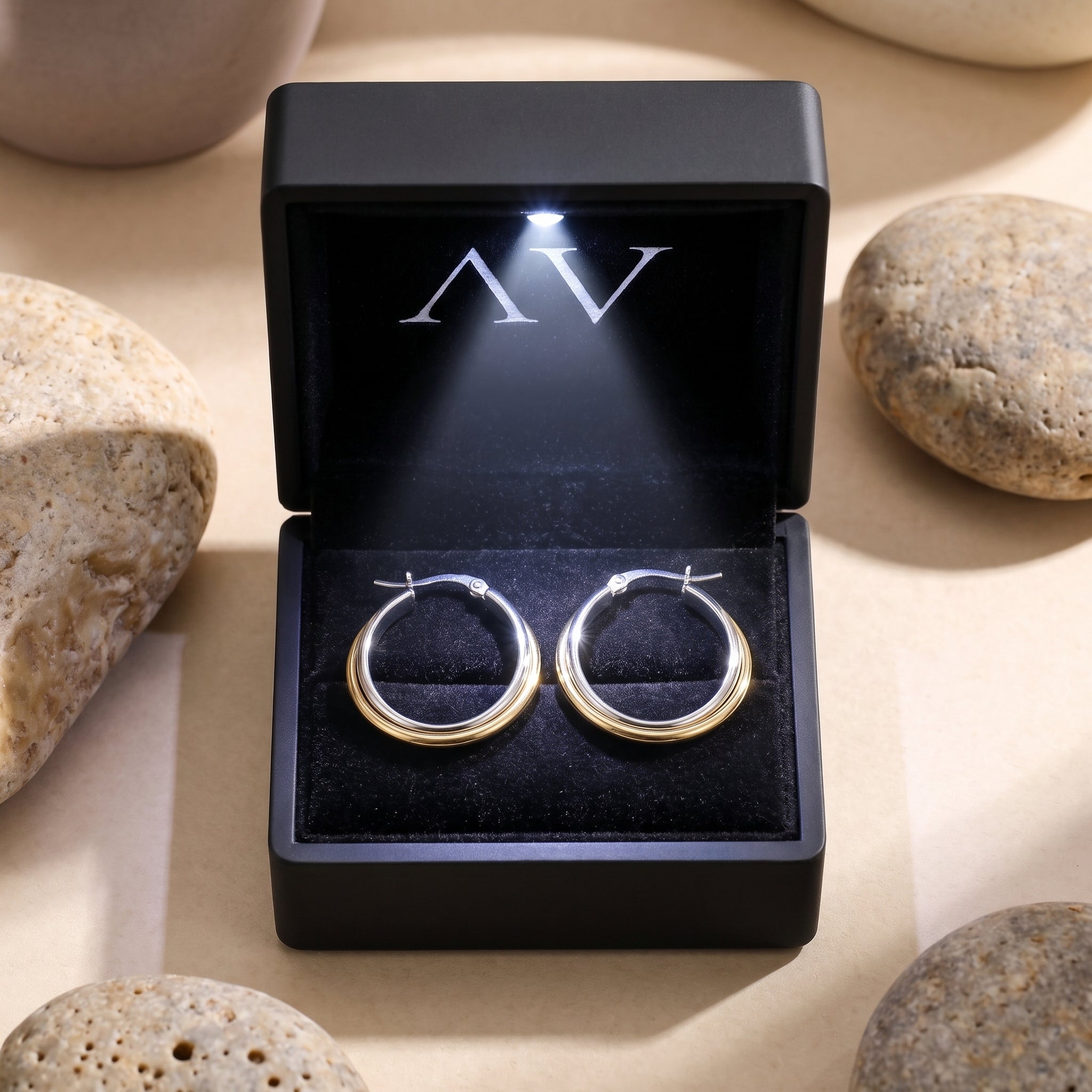 Two-tone interlocking huggie earrings in a black lighted jewelry gift box.