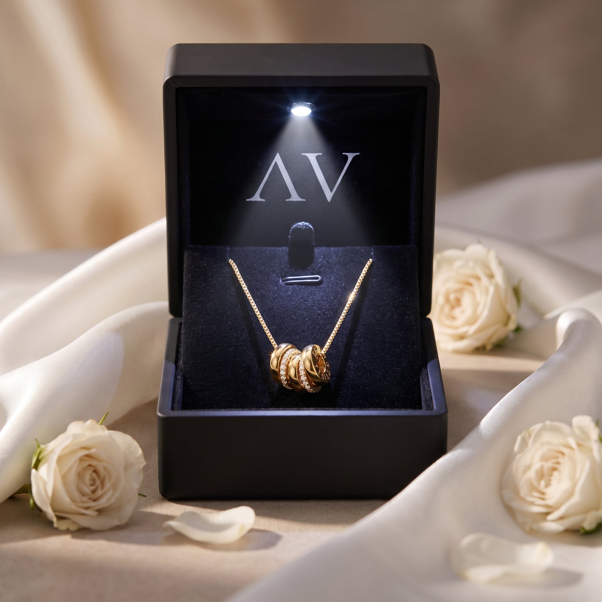 Gold Caelene necklace presented in a black LED-lit gift box with white roses and silk background.
