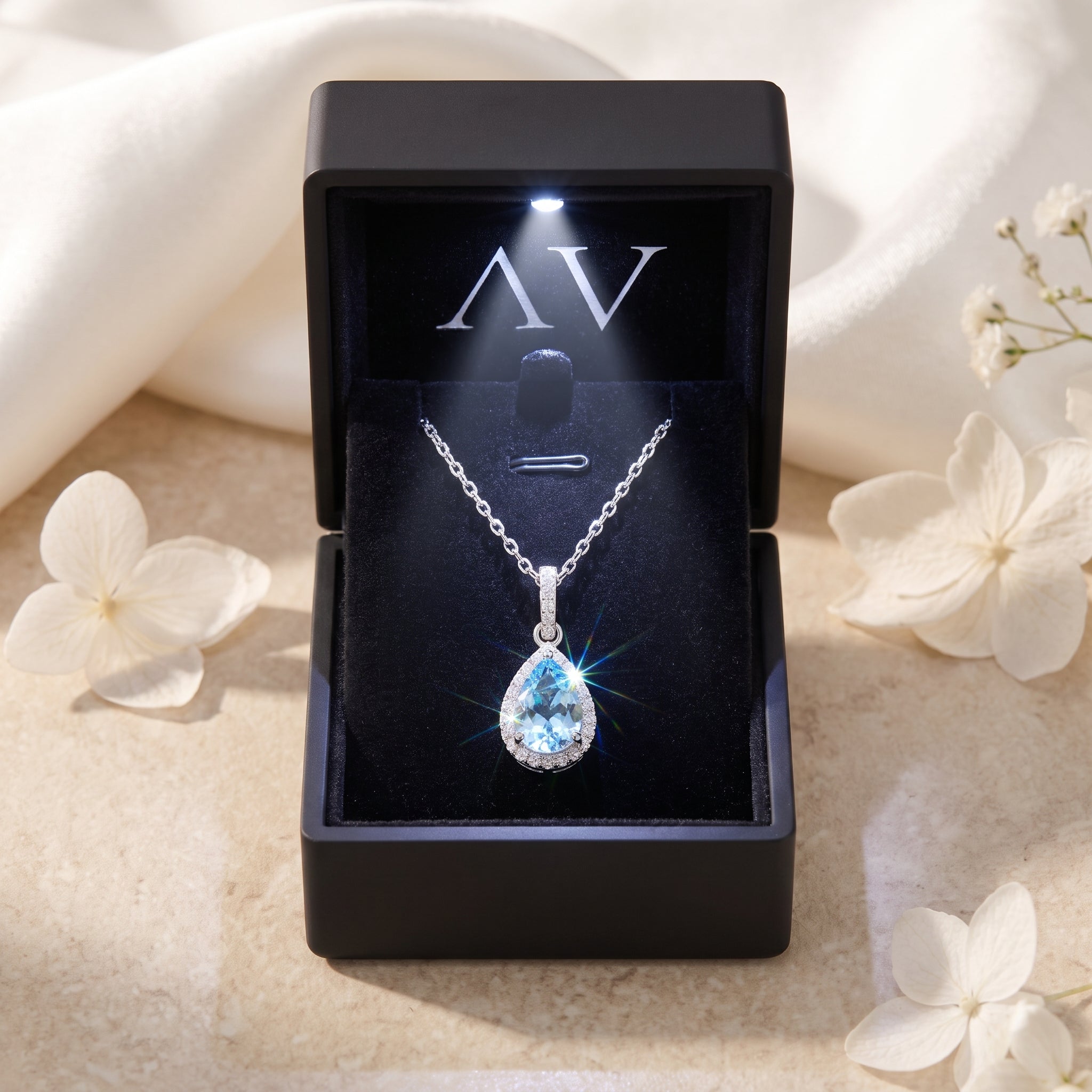 The Caladora aquamarine halo necklace presented in a black LED-lit jewelry gift box.