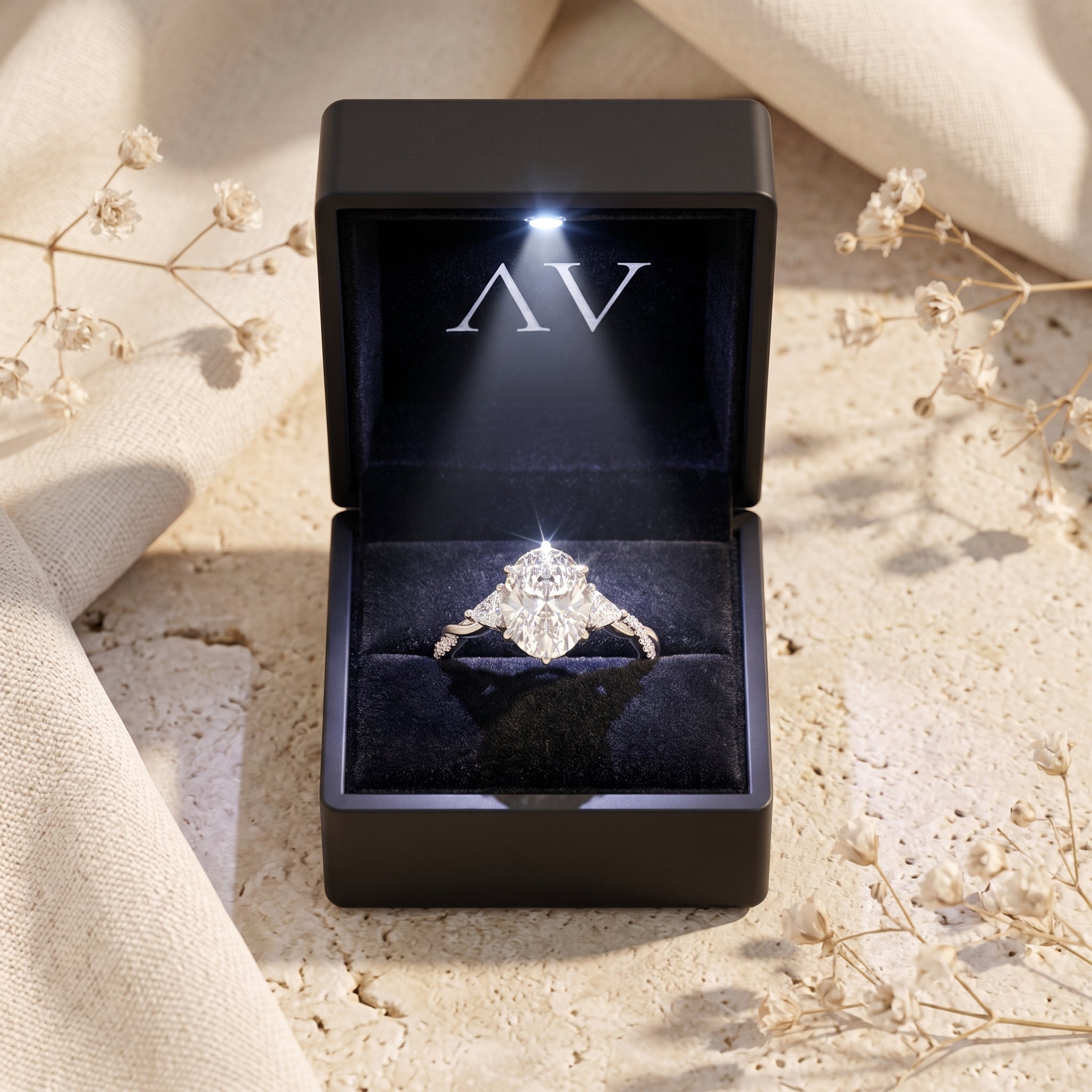 Silver oval moissanite ring inside a black LED-lighted jewelry presentation box.