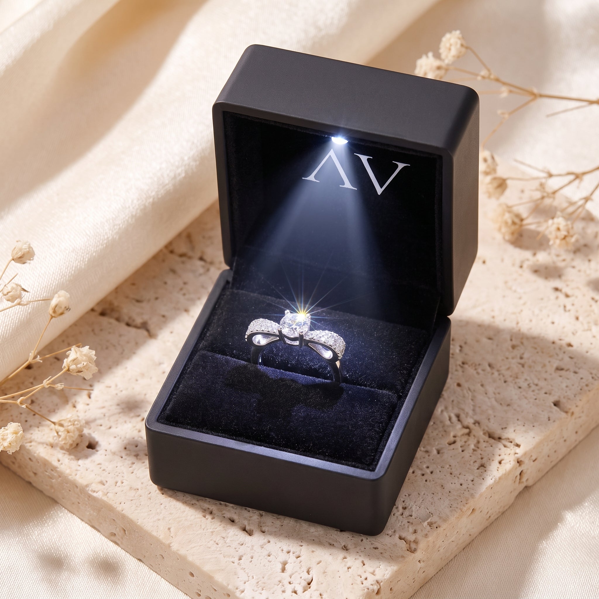 Silver bow promise ring with cubic zirconia inside a black LED-lighted jewelry gift box.