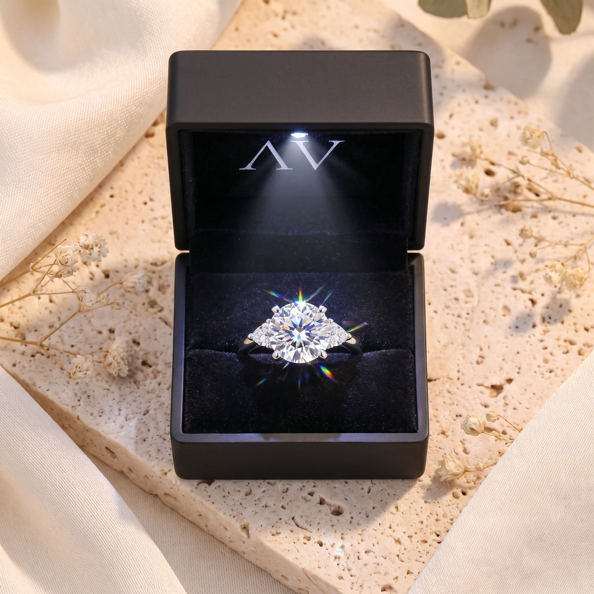 Silver trilogy promise ring in a black LED-lit gift box.