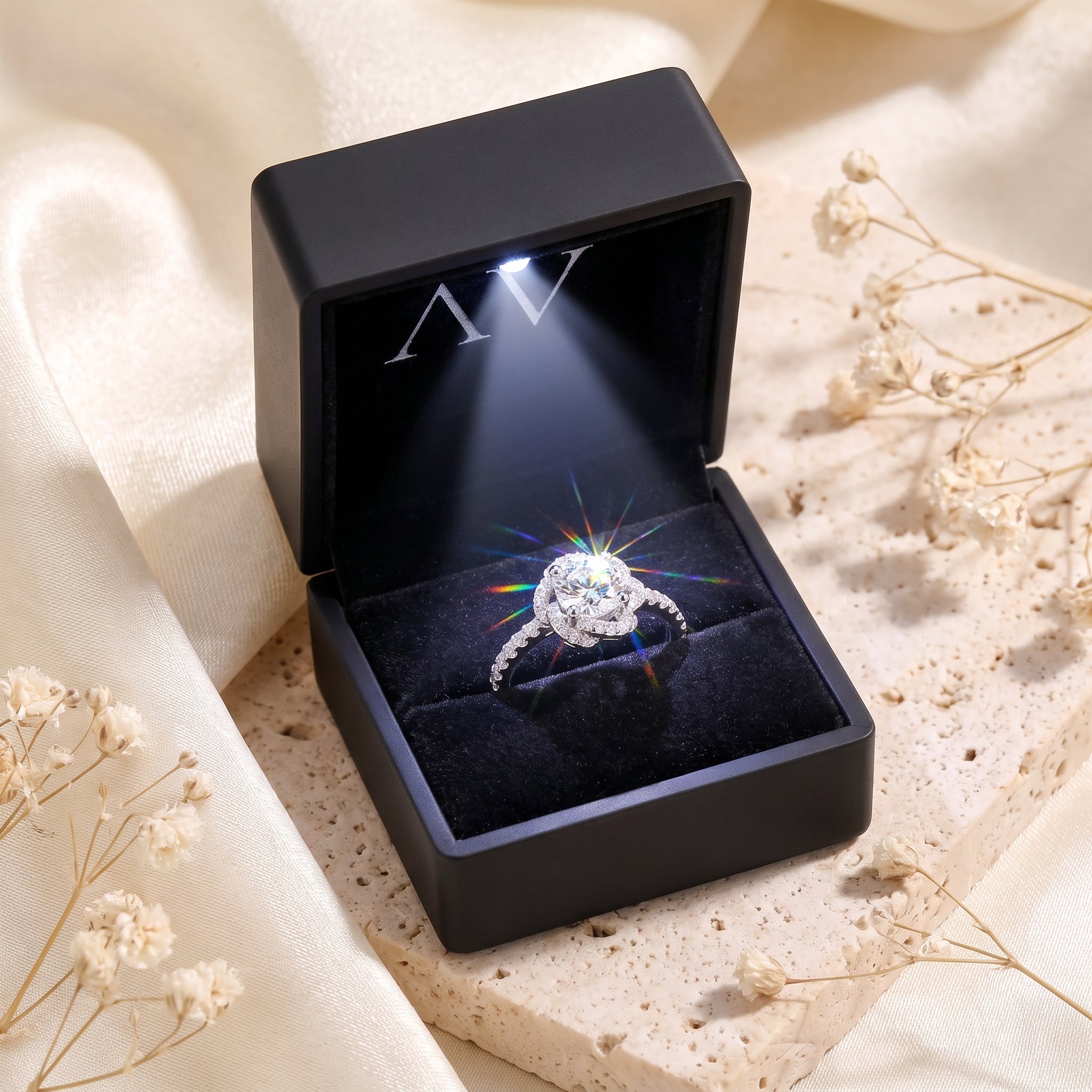 Silver rosette swirl halo ring with round simulated diamond in a lighted black velvet presentation box.