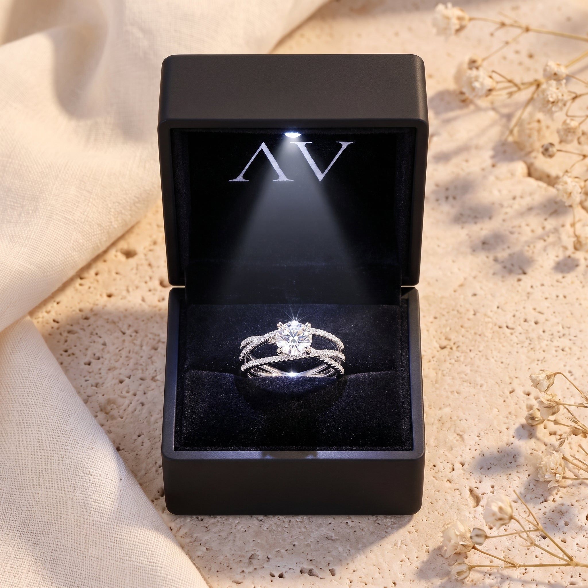 Silver criss-cross solitaire ring presented in a black LED-lit jewelry gift box.