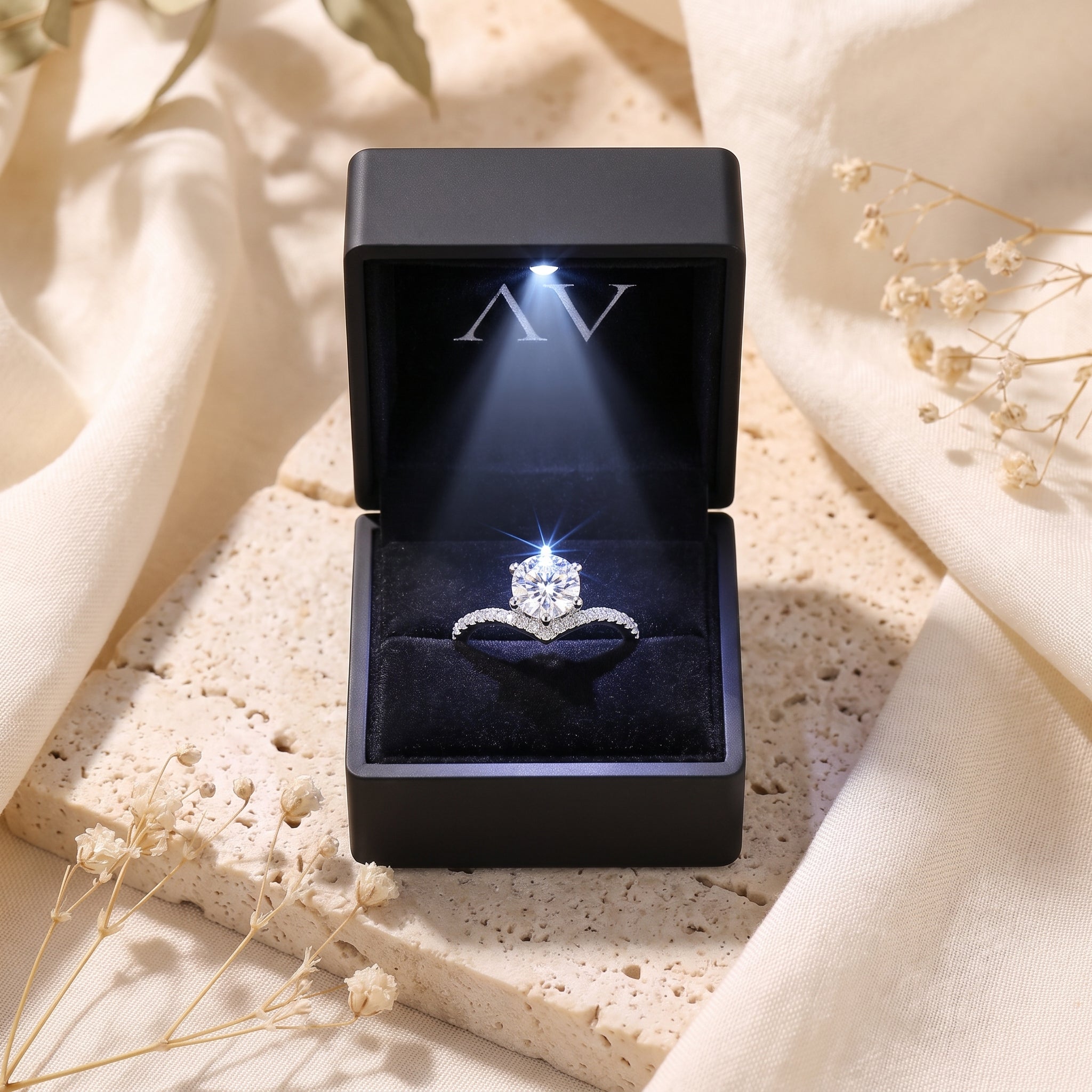 Silver chevron solitaire ring in a lighted black jewelry box.