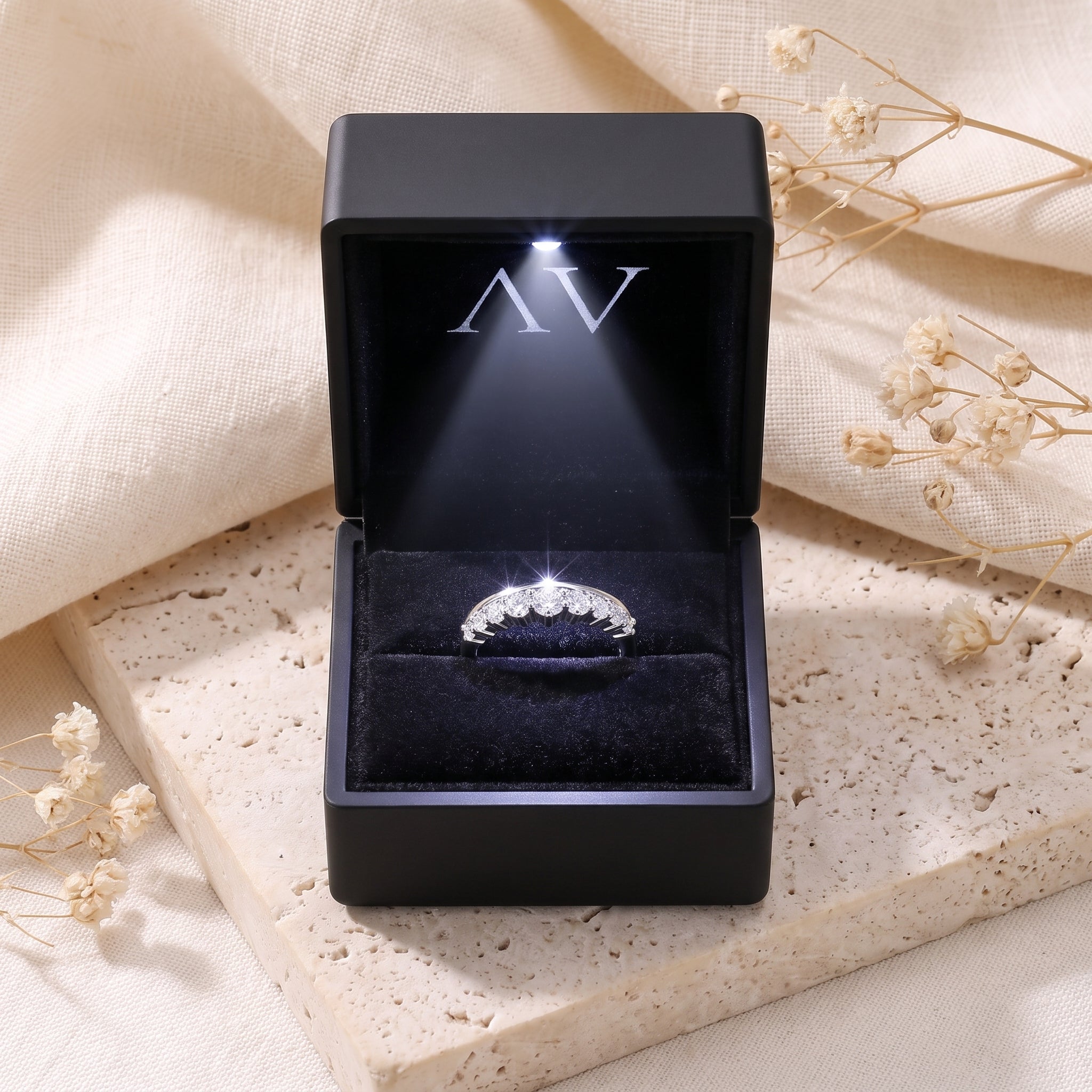 Silver curved ring with cubic zirconia in a black LED-lit gift box.