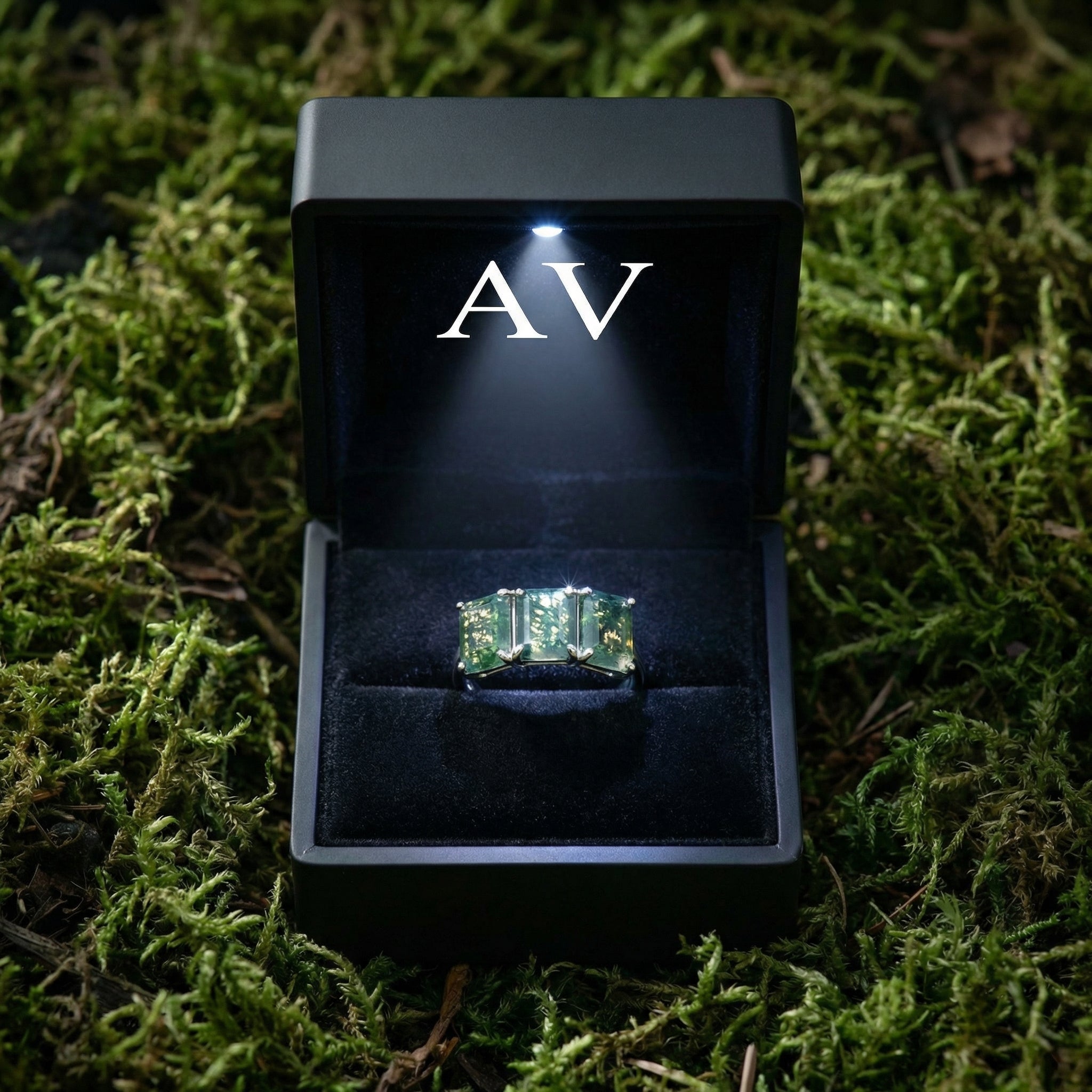 Triple moss agate bar ring presented in a black LED-lighted gift box on a bed of forest moss.