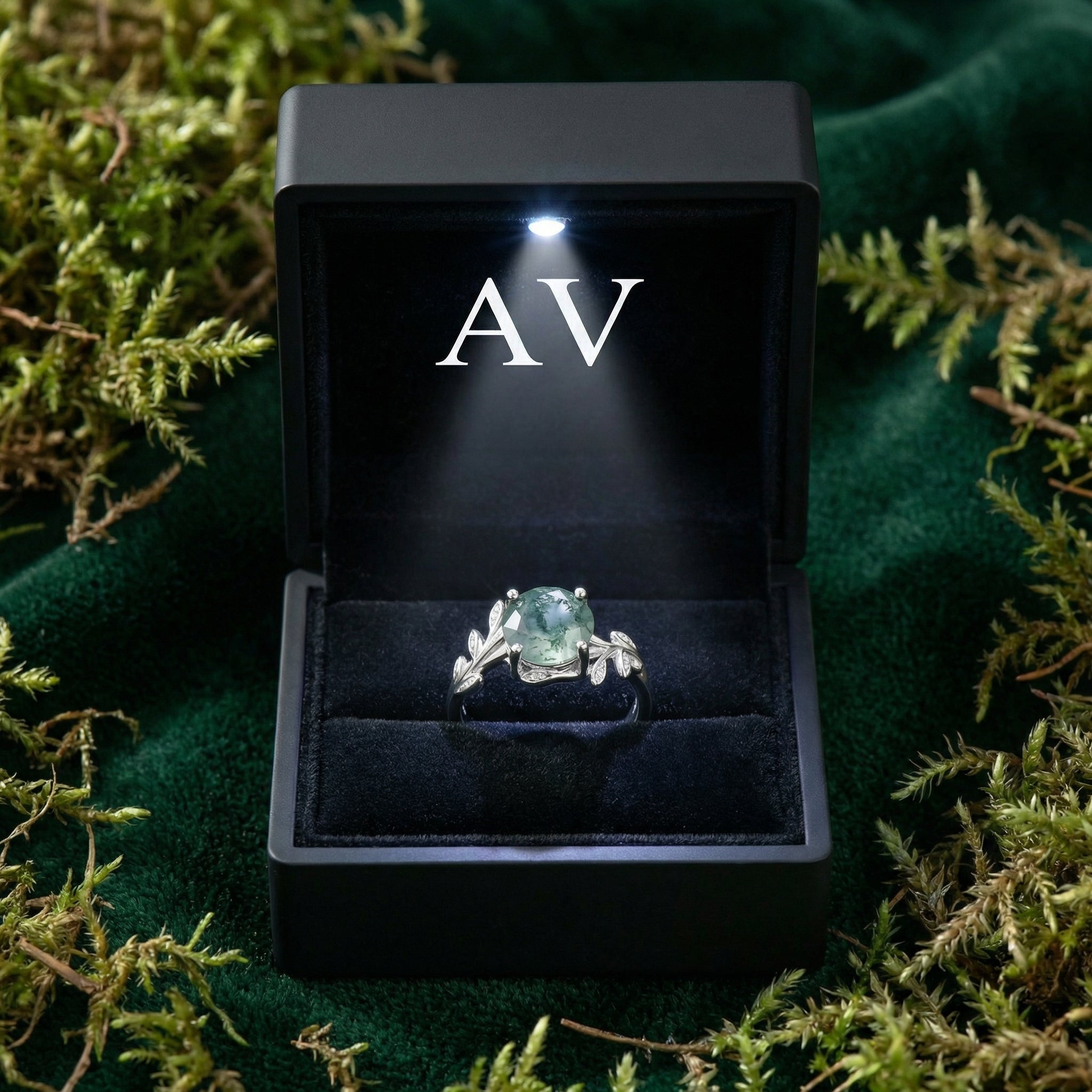 Silver moss agate ring presented in a black LED-lit gift box on a bed of green moss and velvet.