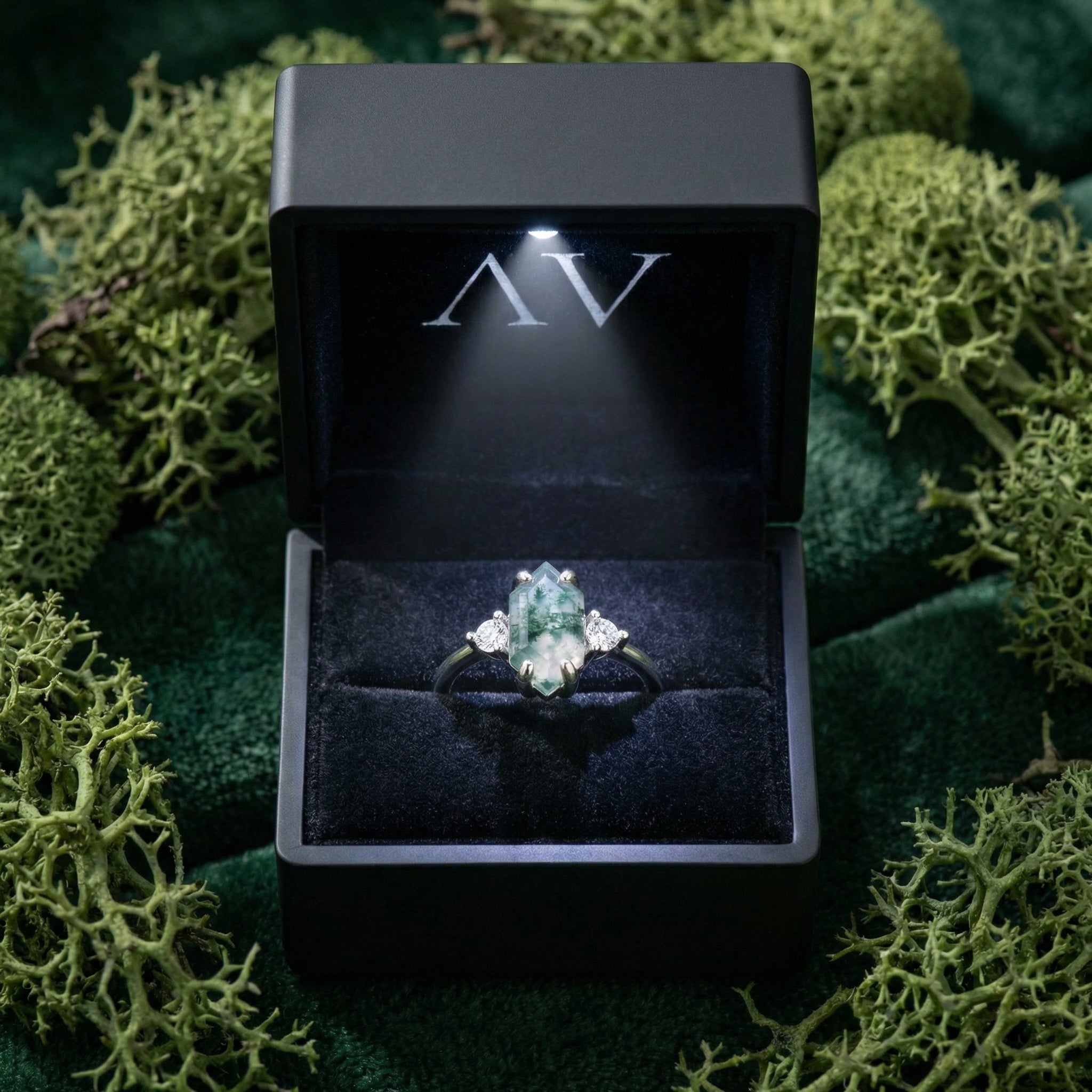 Moss agate sterling silver ring inside a black LED-lit gift box on a bed of natural green moss.