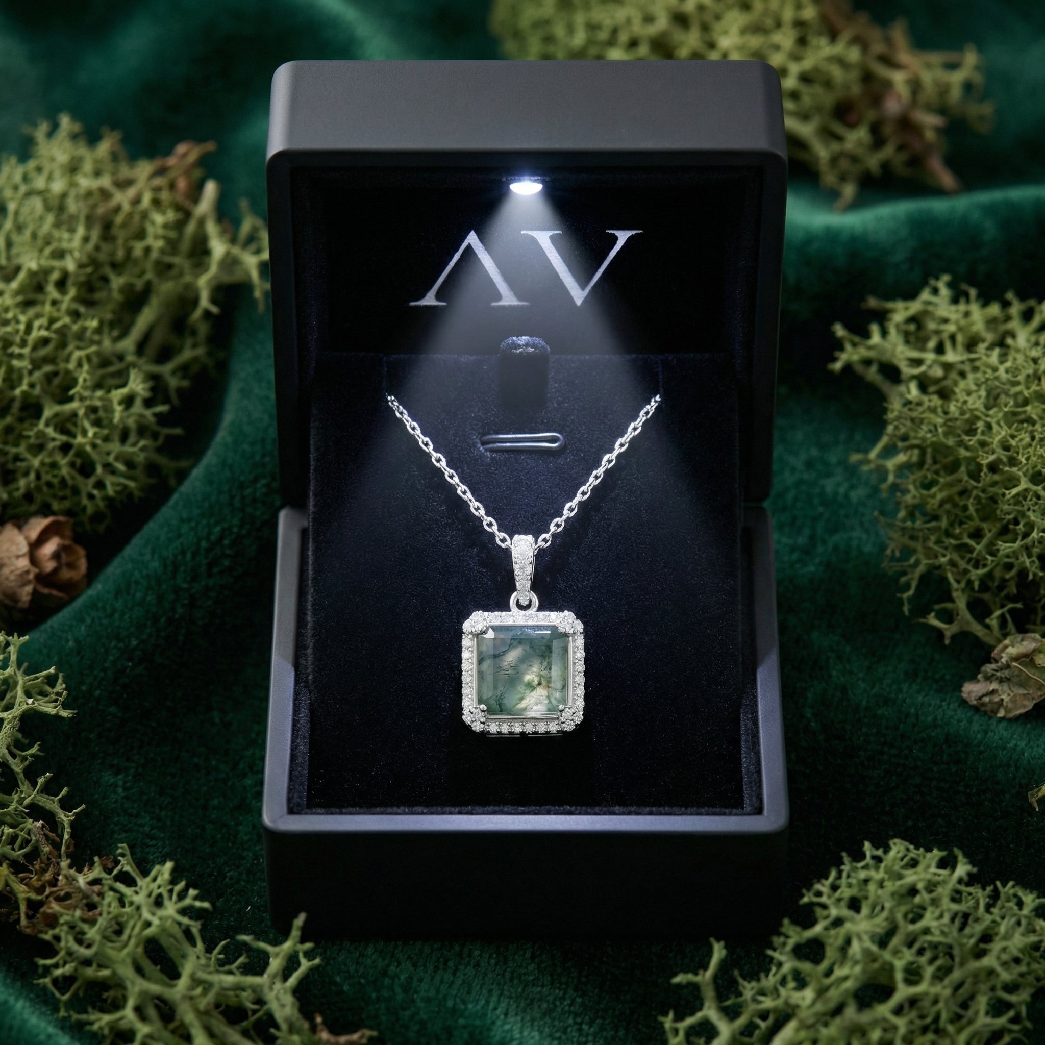 Square cut moss agate halo pendant necklace inside a black LED-lit gift box on a green velvet background.