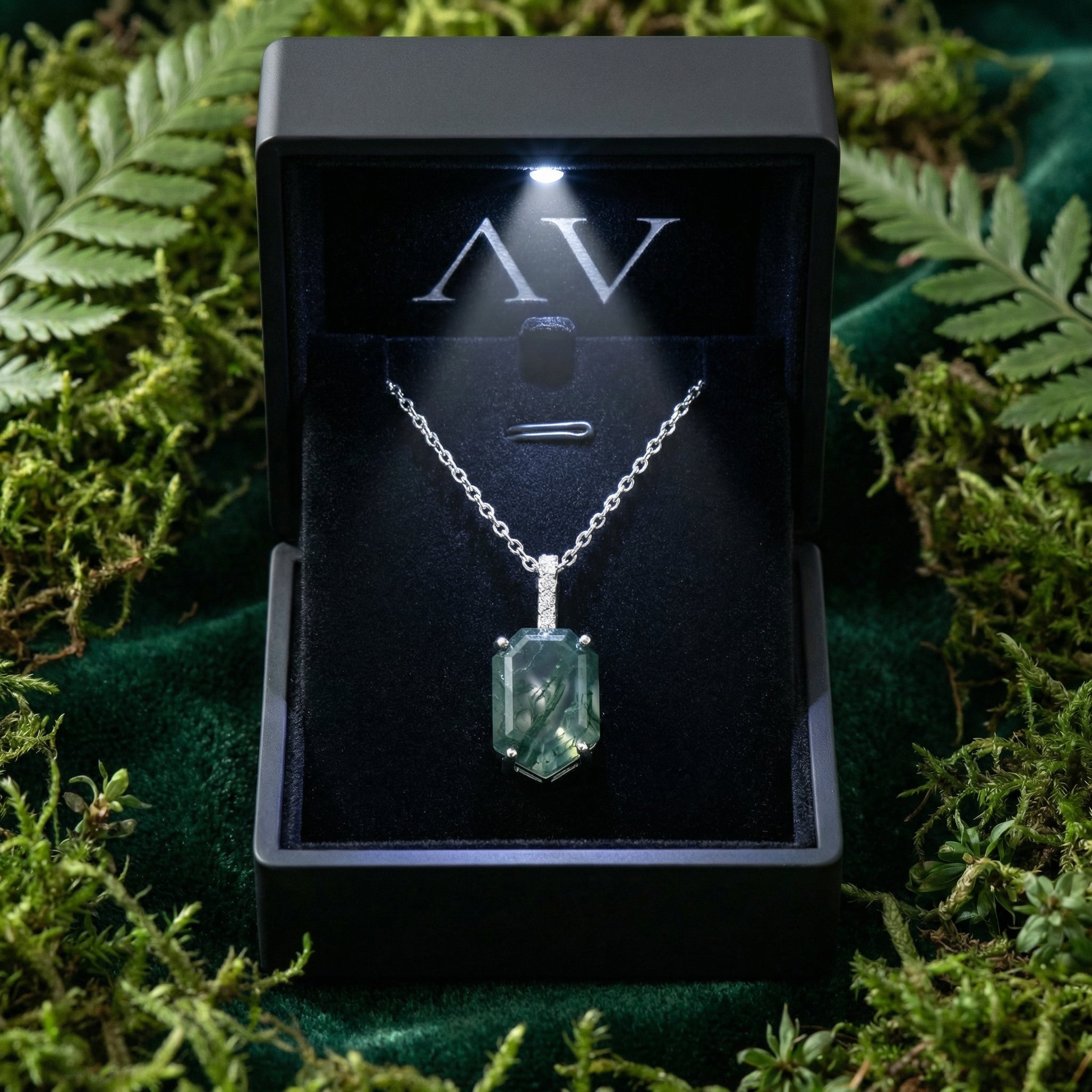 Sterling silver moss agate column pendant necklace presented in a lighted black gift box surrounded by green moss.