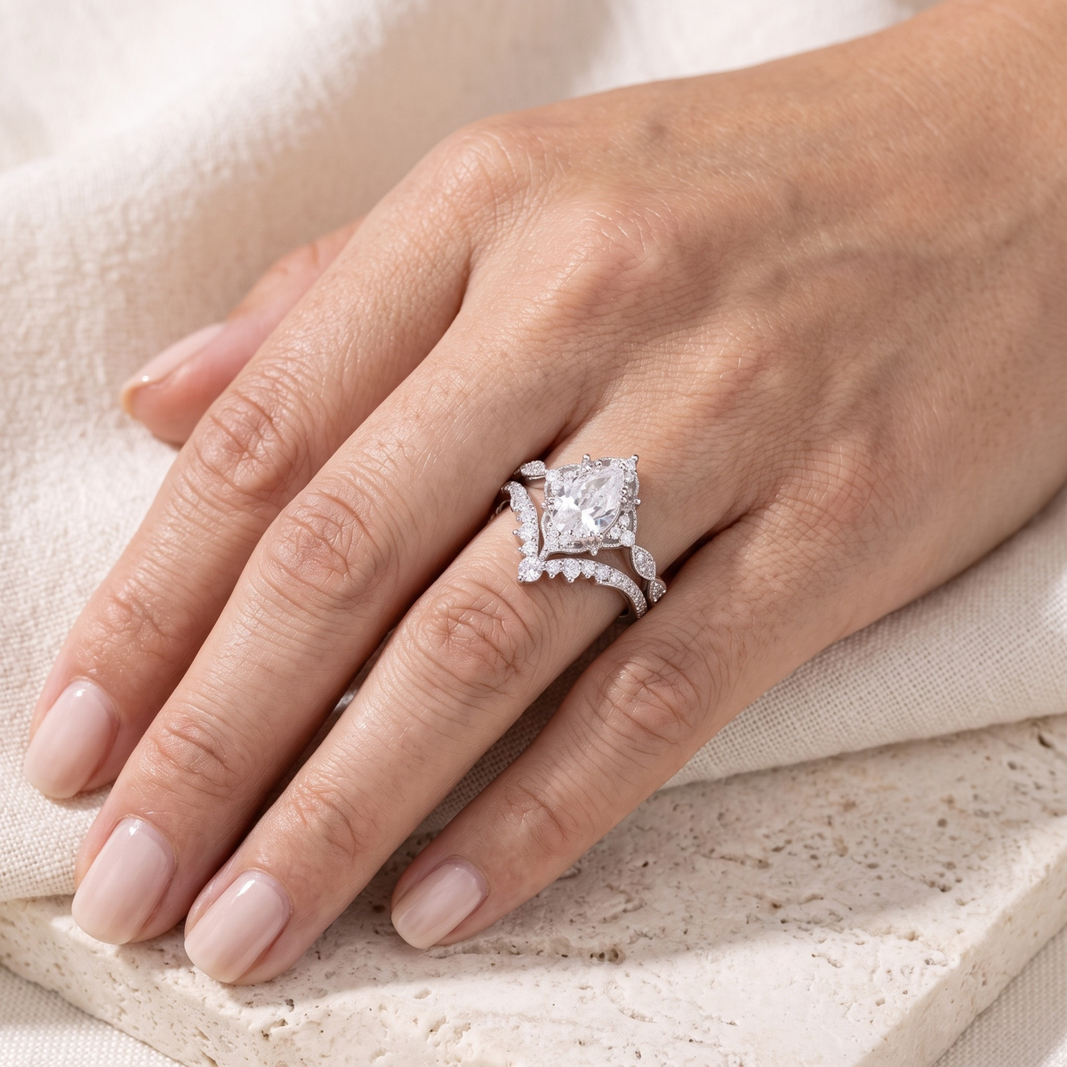 Vintage pear-cut ring and matching curved band in silver worn on a model's hand.