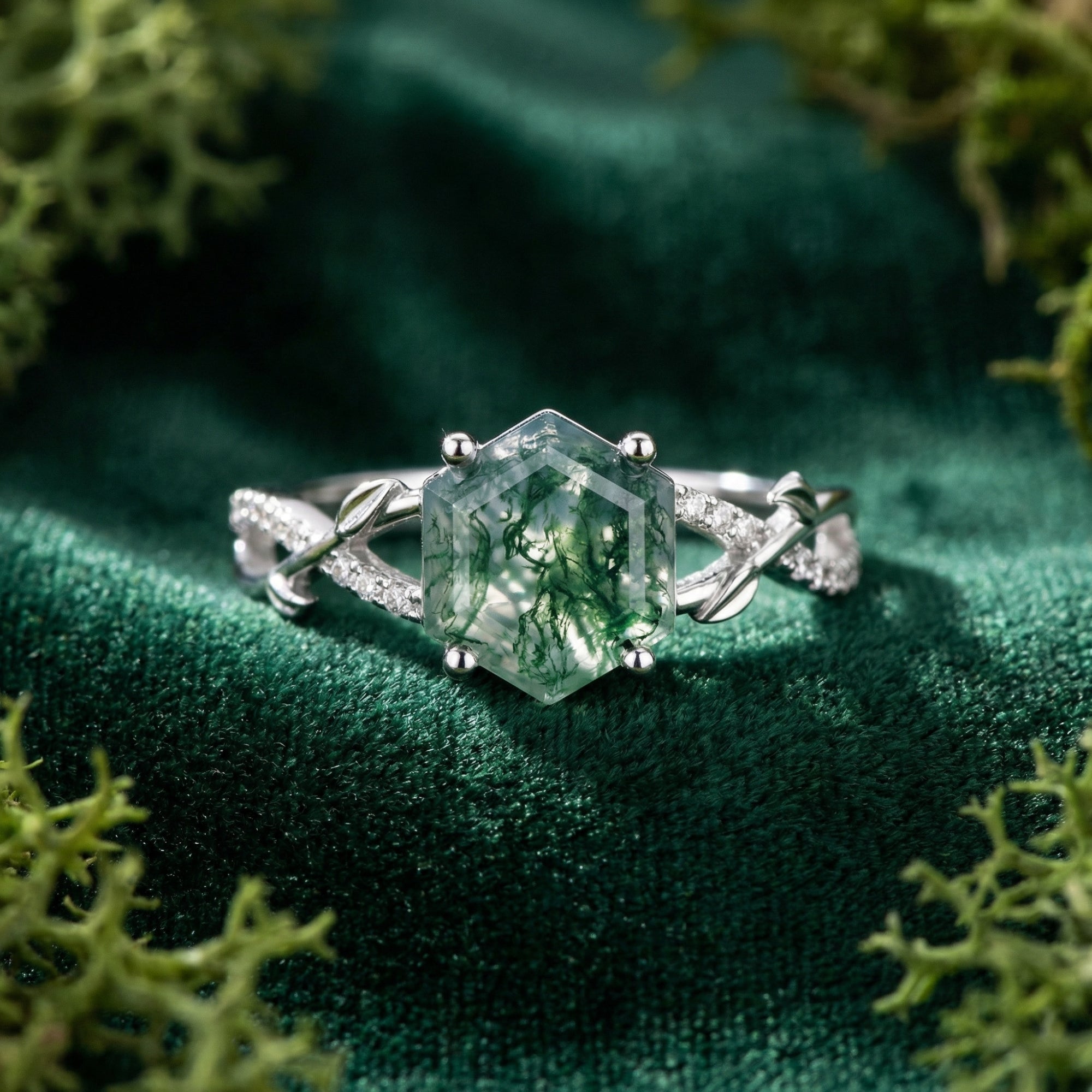 Hexagonal cut natural moss agate ring in S925 sterling silver with diamond leaf accents on green velvet.