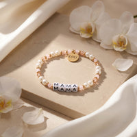 Beaded 18K gold bracelet with pearls and MAMA charms in a floral lifestyle setting.