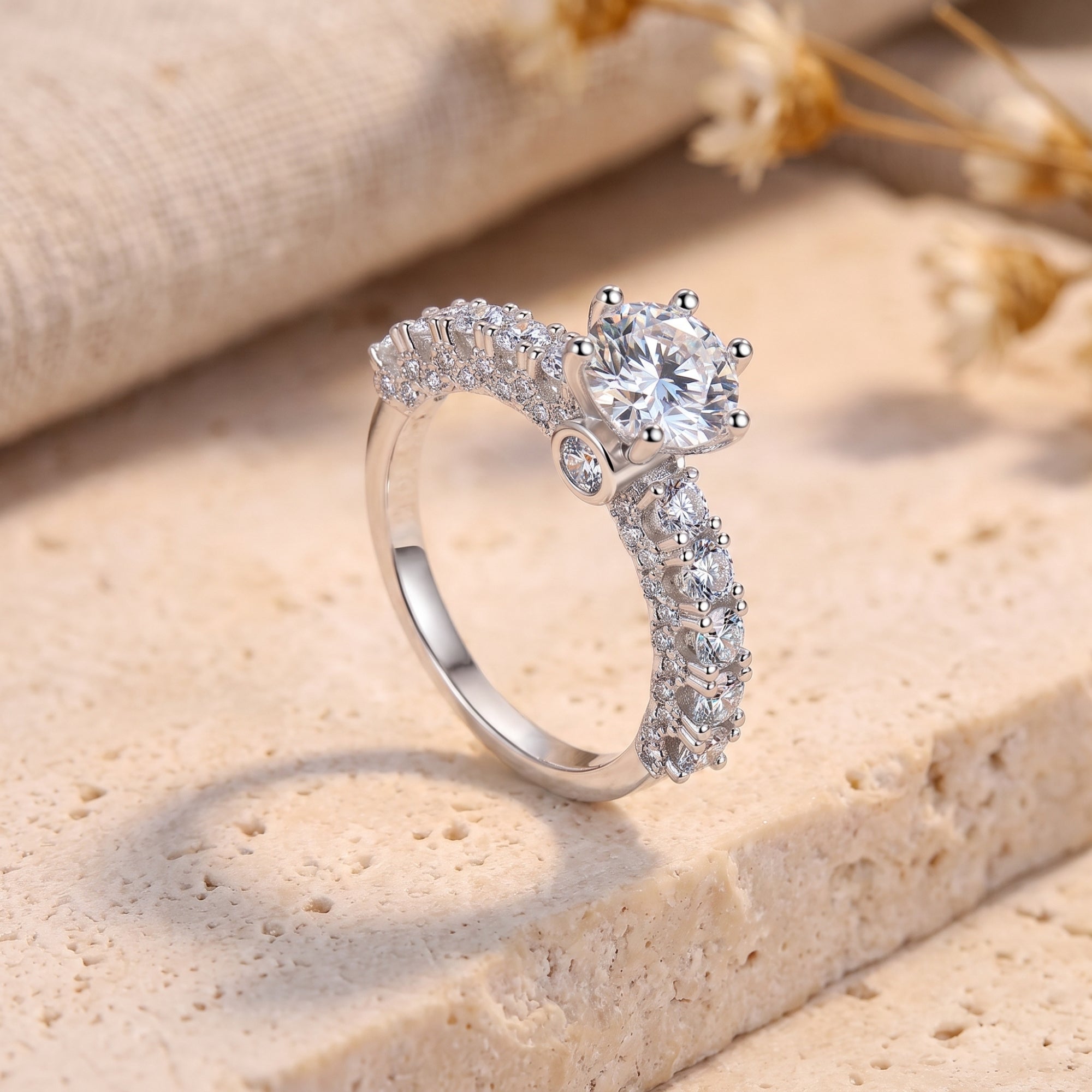 Silver promise ring with round cubic zirconia in a crown setting on a stone surface.