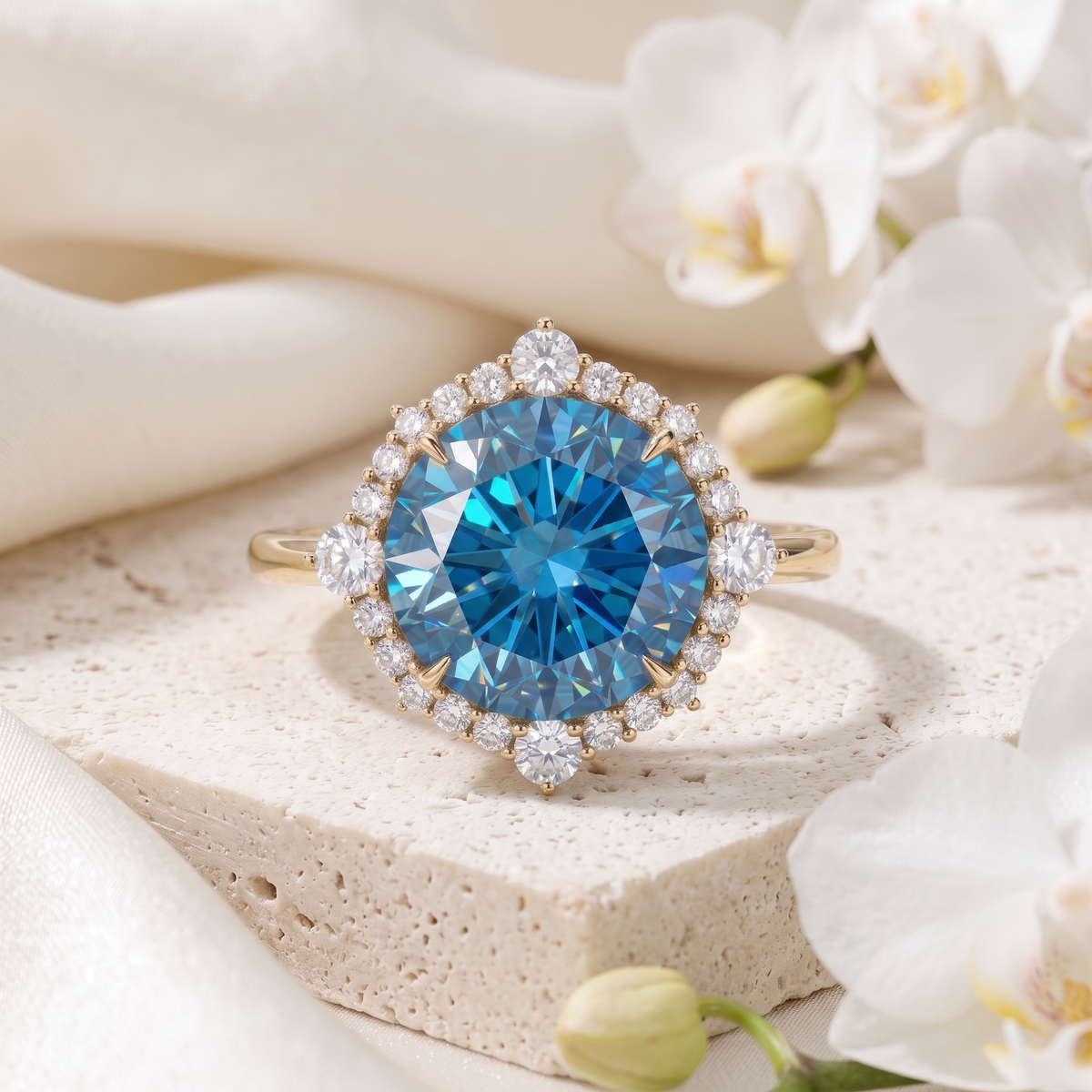 Yellow gold blue moissanite halo ring with a large round center stone presented on a travertine block.