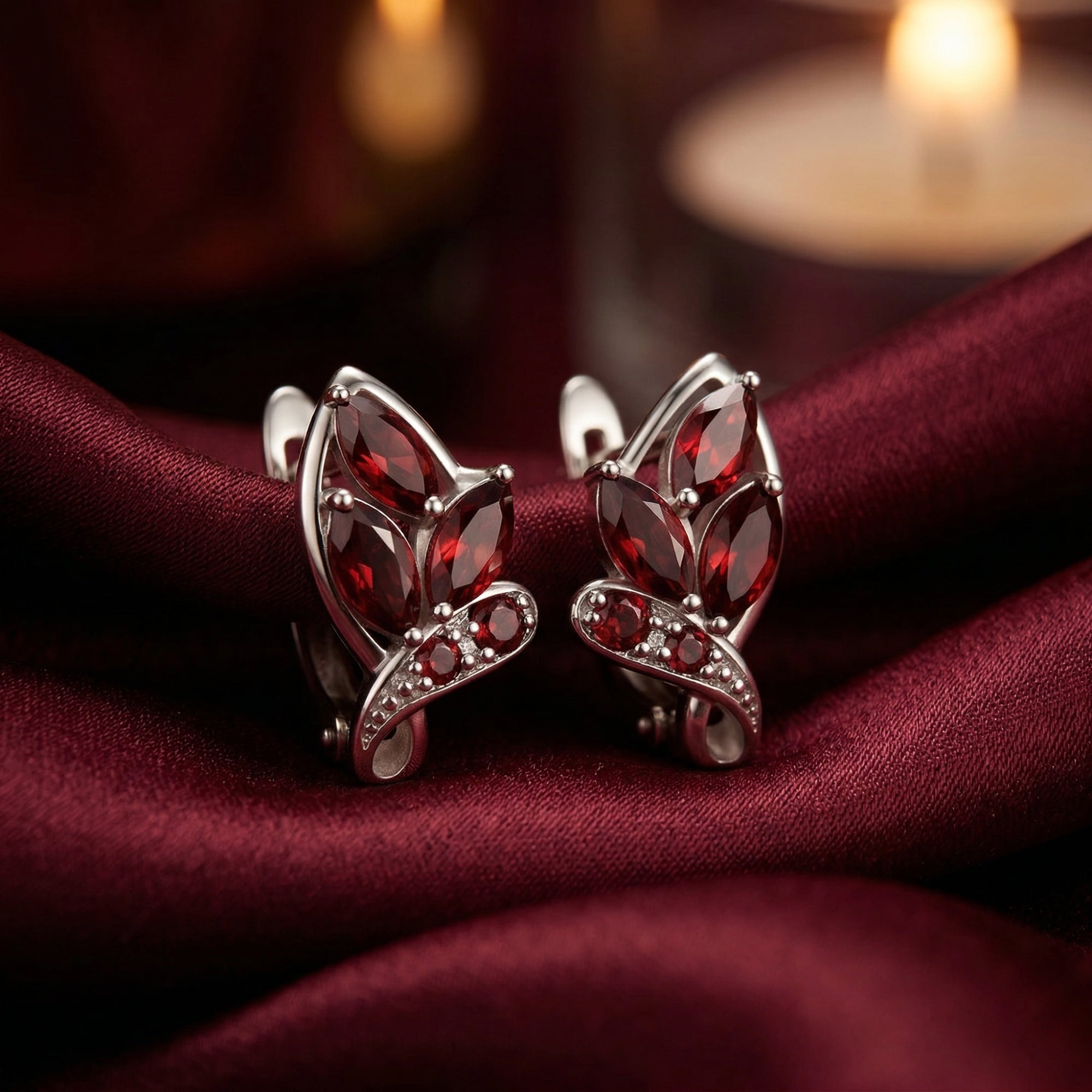 Natural marquise and round garnet drop earrings in sterling silver on a red silk background.