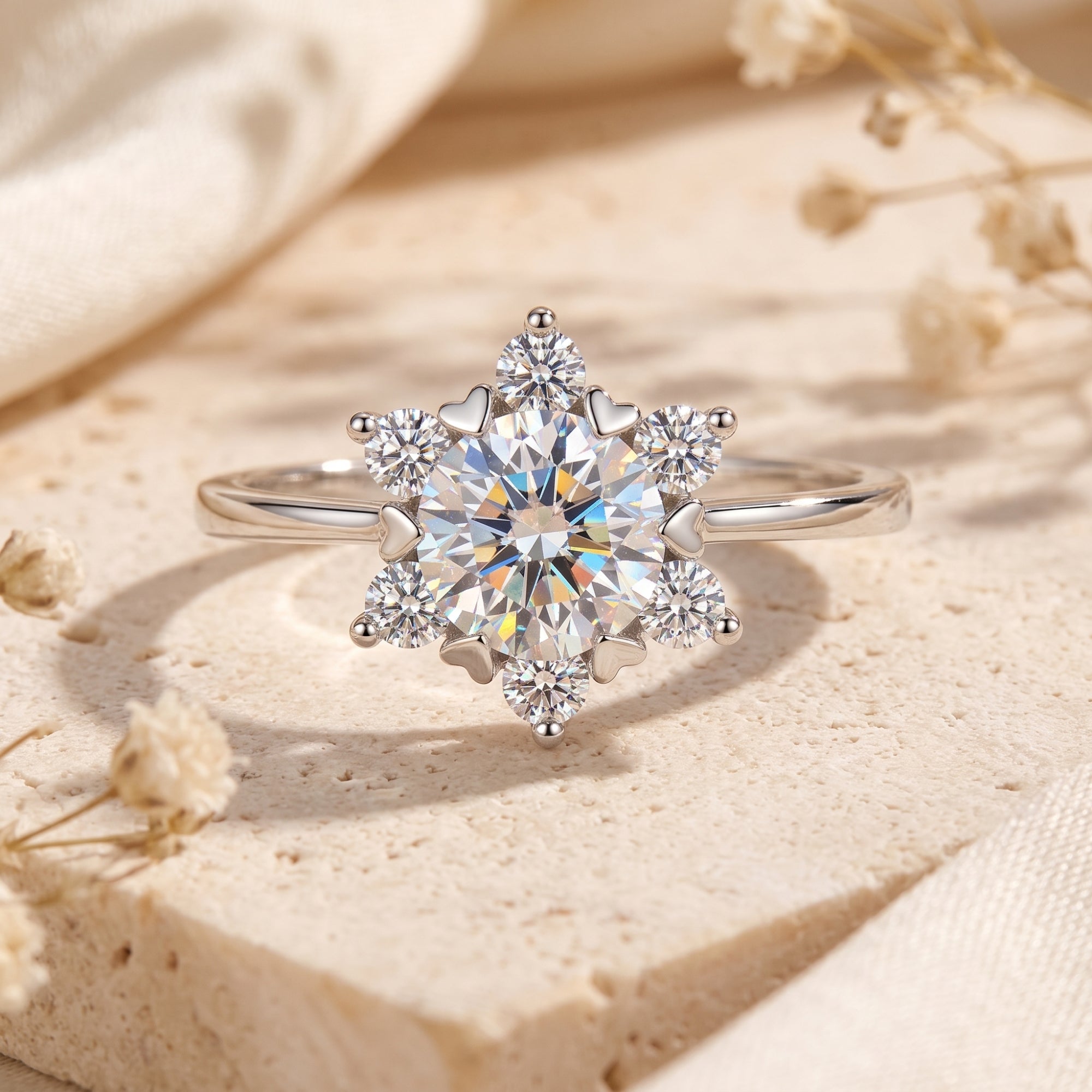 Sterling silver snowflake cluster ring with round simulated diamonds on a stone surface.