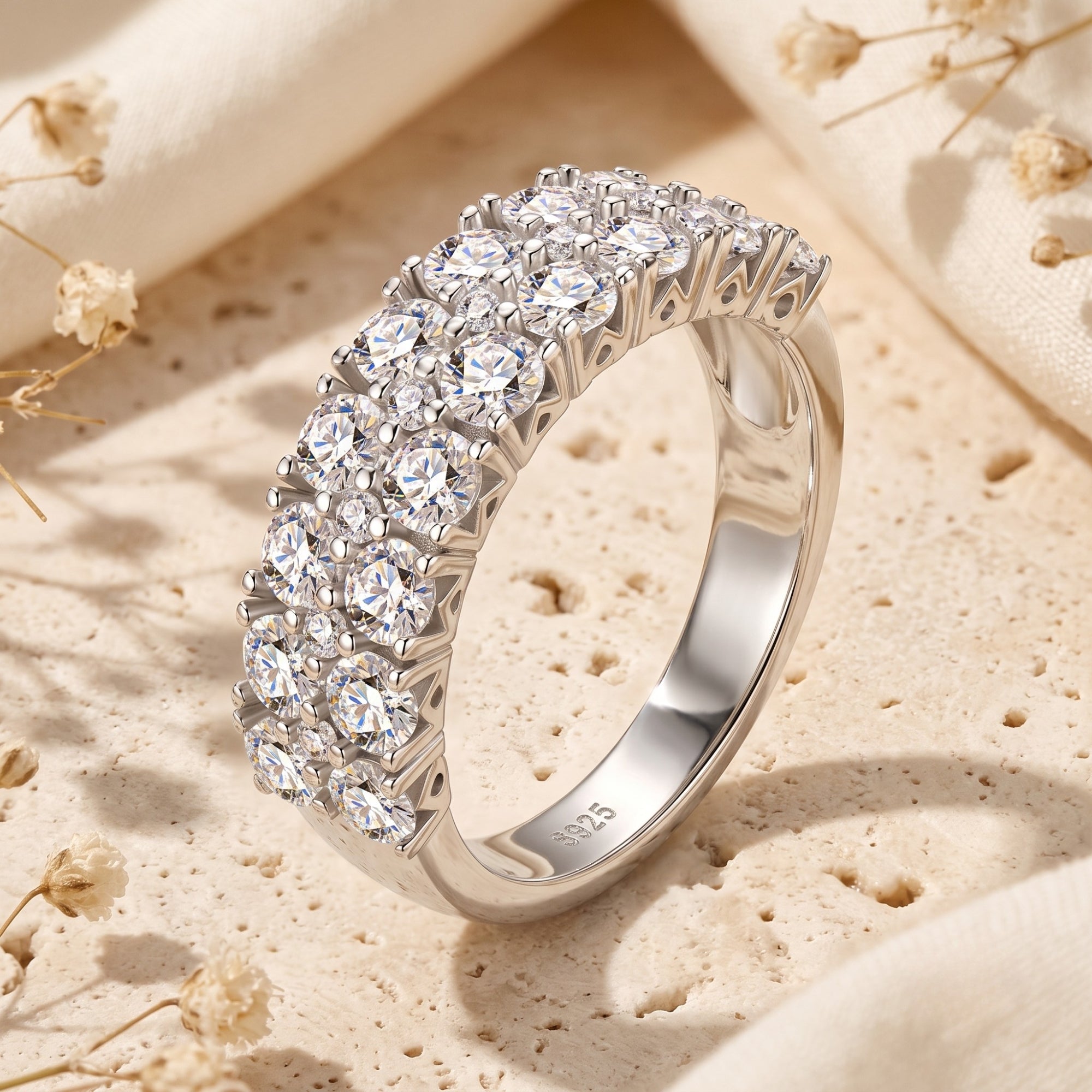 Triple row sterling silver ring with round cubic zirconia on a textured stone lifestyle background.