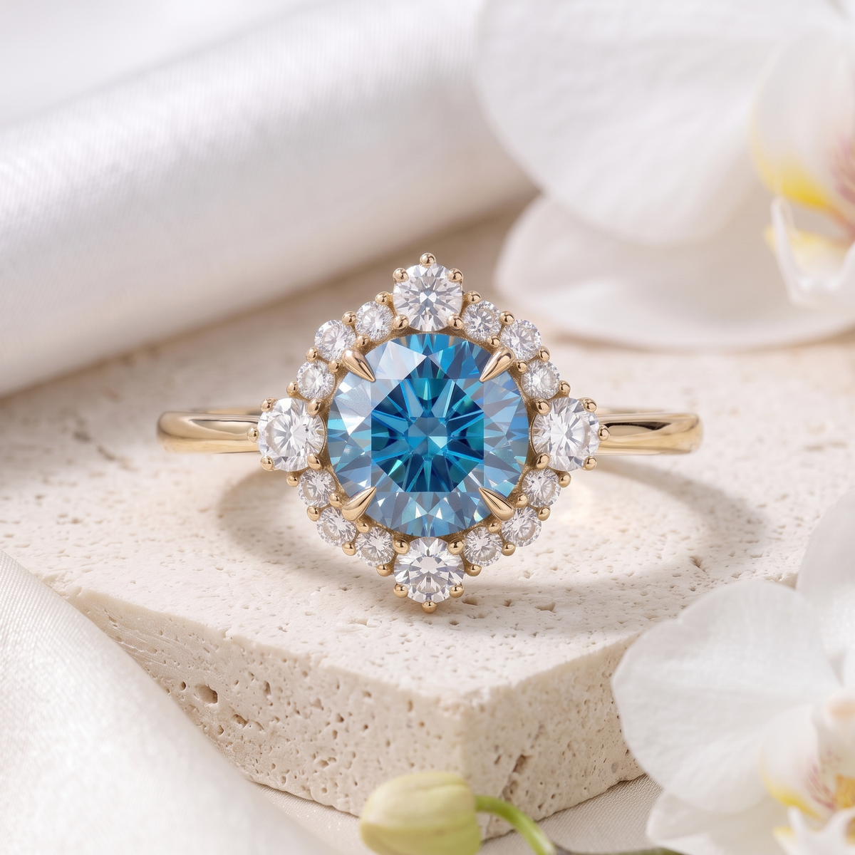 Yellow gold halo engagement ring featuring a round brilliant-cut blue moissanite center stone accented with a diamond-shaped halo of round moissanites.