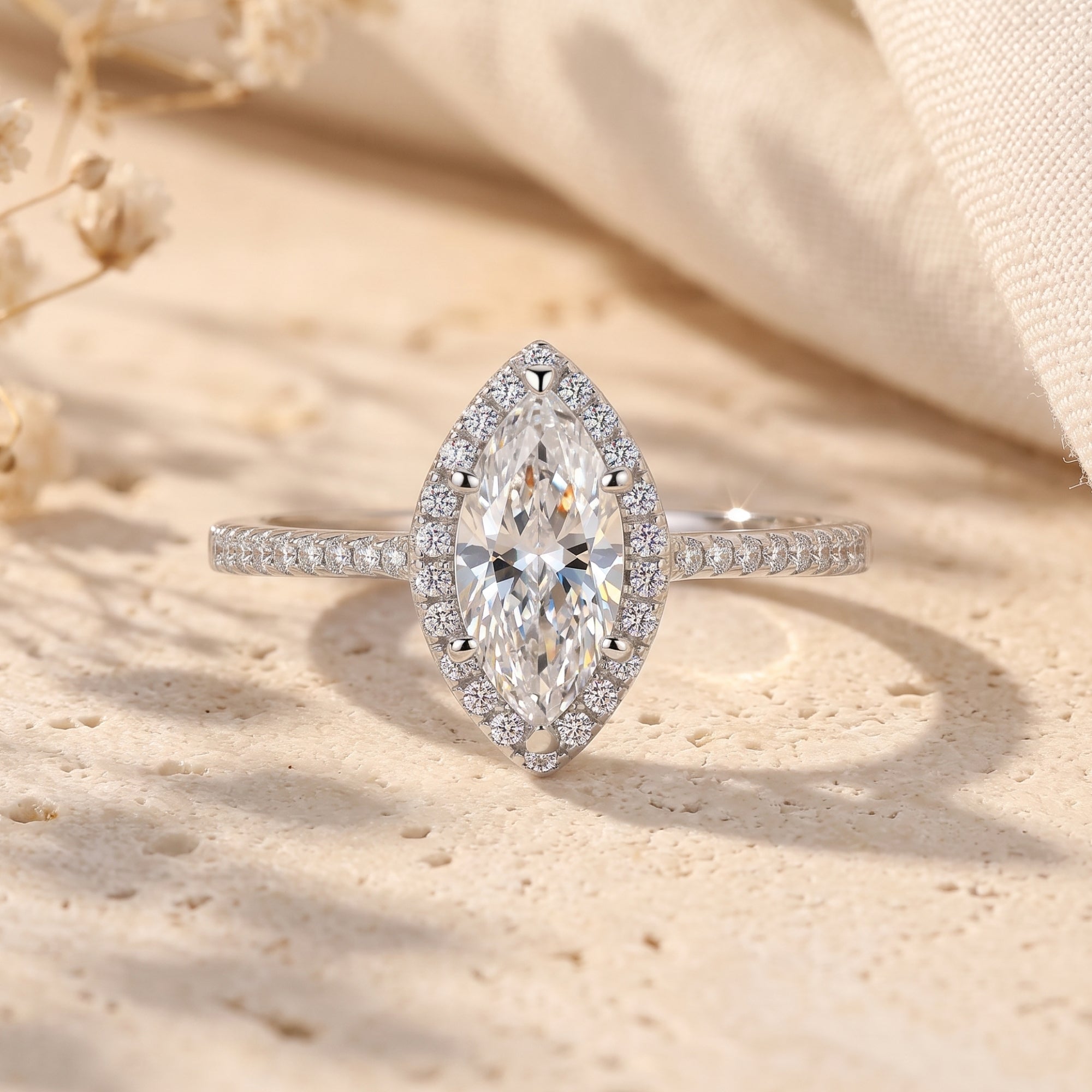 Marquise cut simulated diamond halo promise ring in S925 sterling silver on a textured lifestyle background.