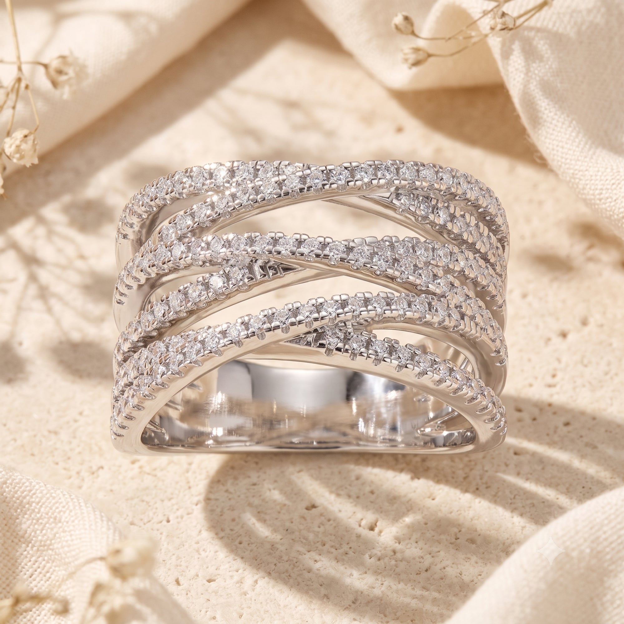 Nexus crossover ring in S925 sterling silver with pavé simulated diamonds on a styled surface.