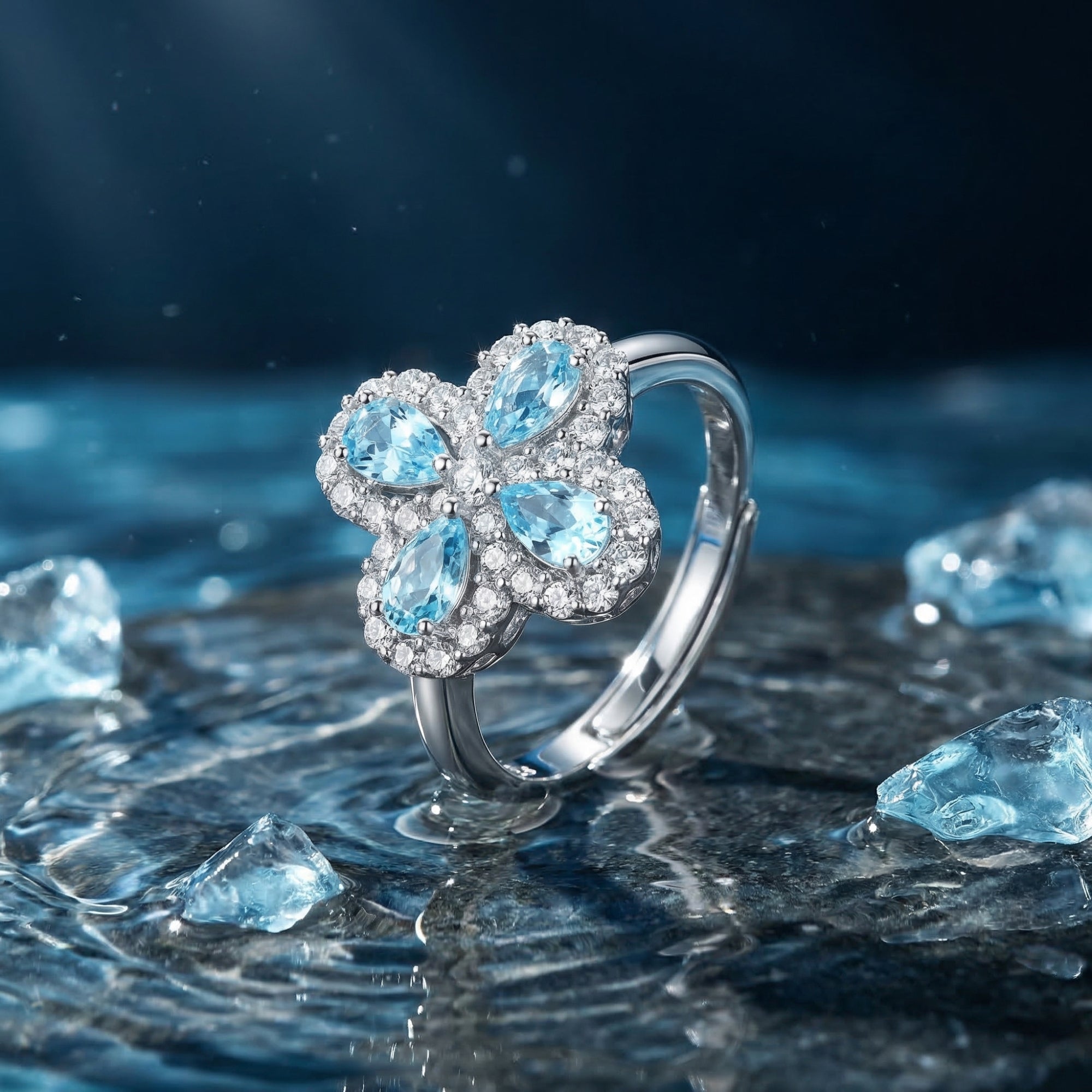 Silver pear-cut aquamarine clover ring on a wet stone background with water ripples and ice crystals.