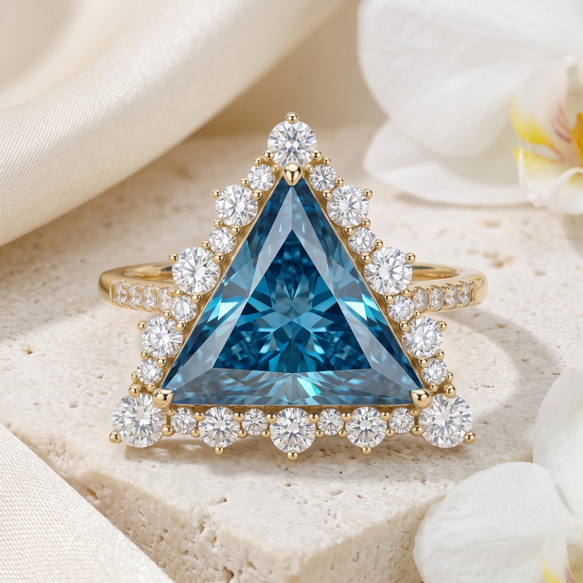 Front view of a trillion cut blue moissanite halo ring in yellow gold resting on a stone display.