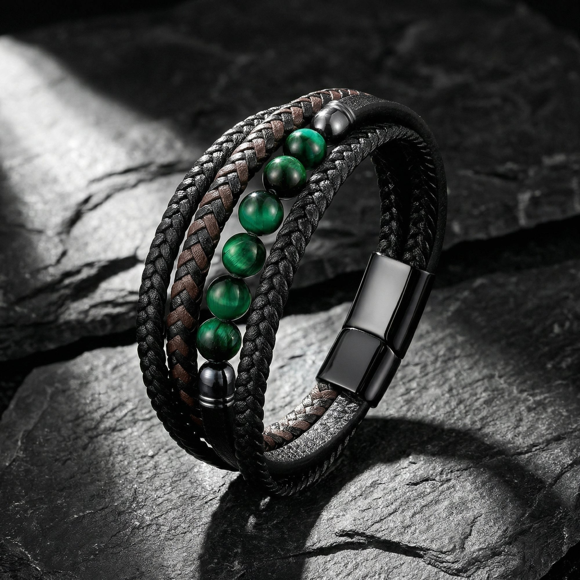 Multi-strand black and brown braided leather bracelet with green tiger eye beads on a dark stone background.