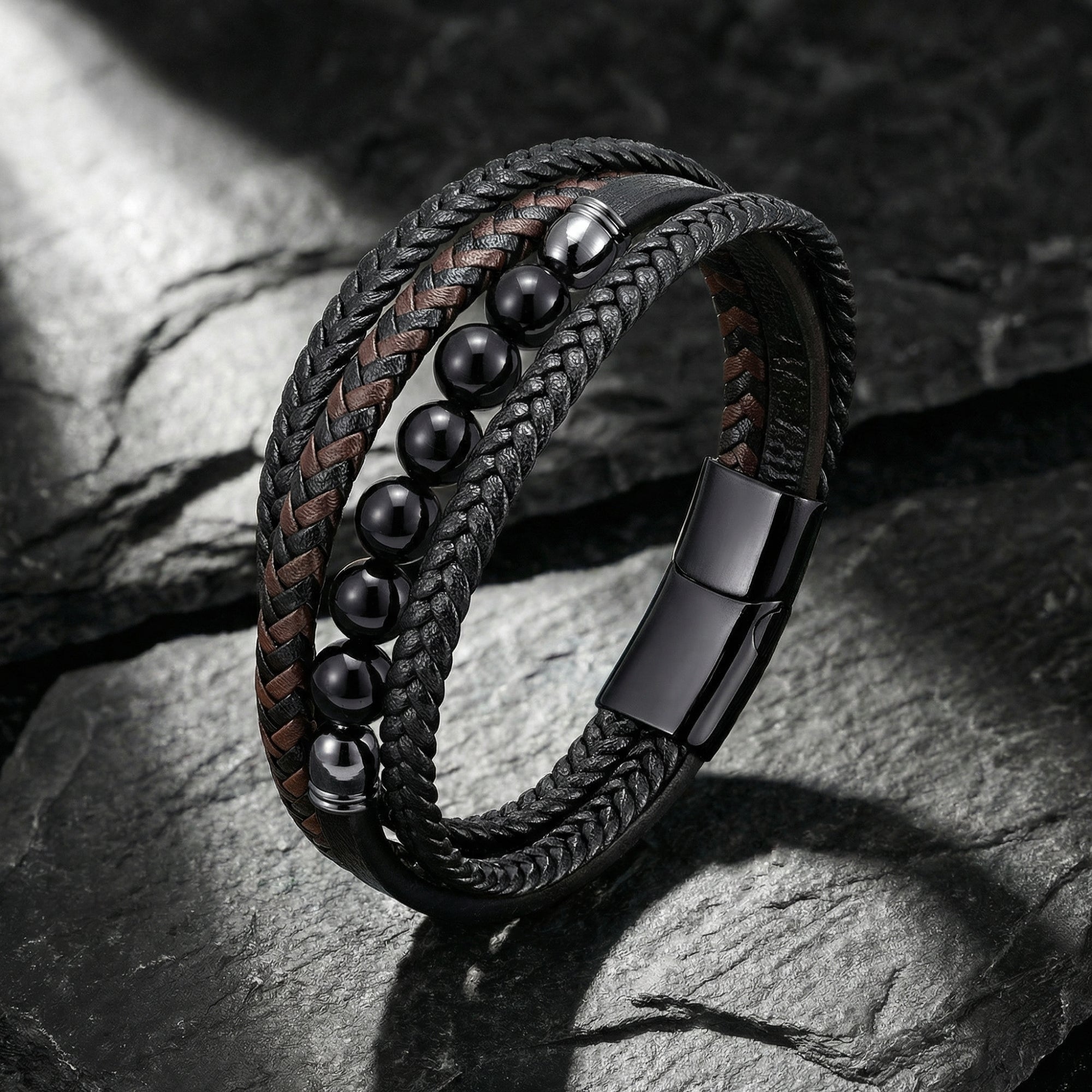Men's multi-strand black and brown braided leather bracelet with black beads and black stainless steel clasp on stone.