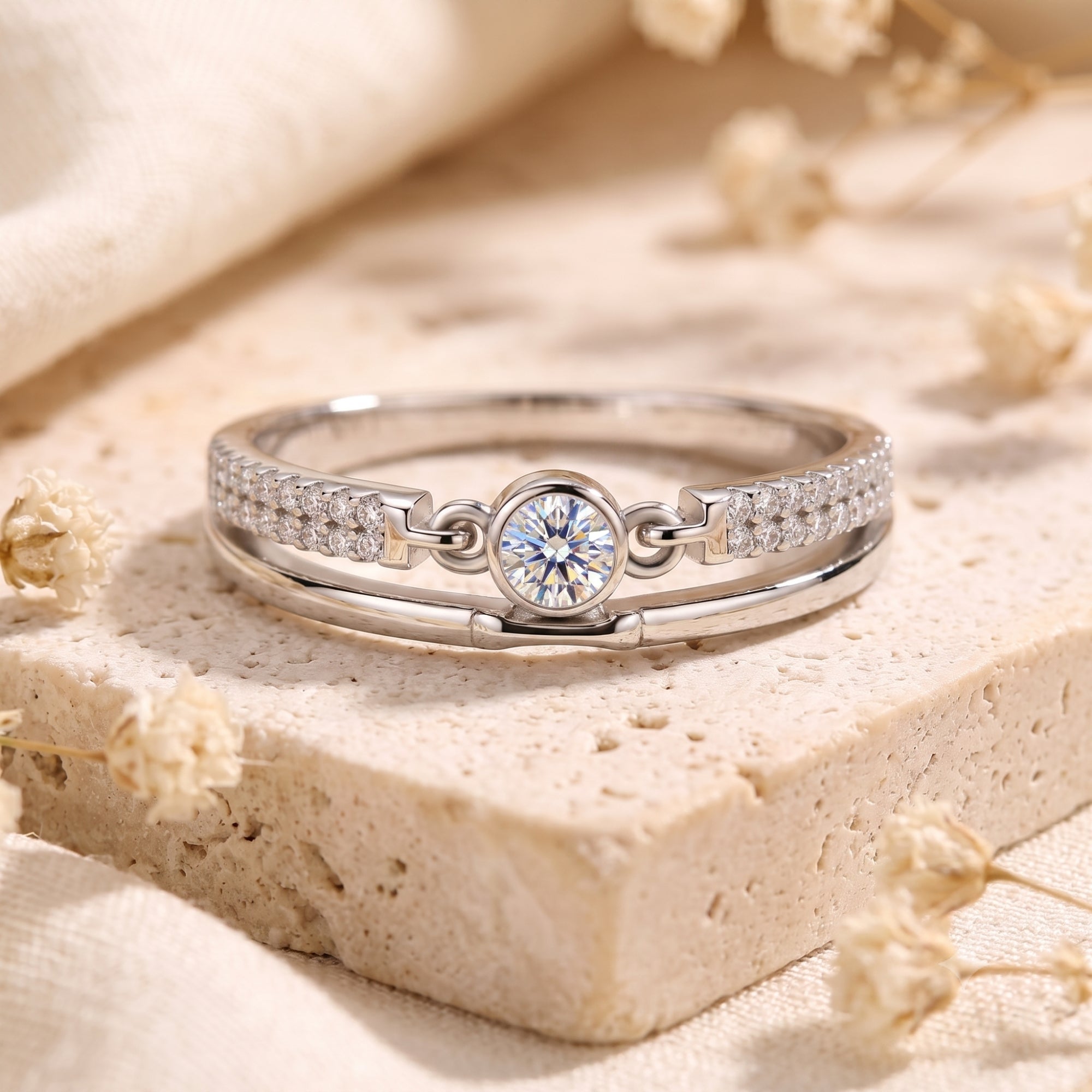 Lyra S925 silver double band ring with round cubic zirconia on a stone and floral background.