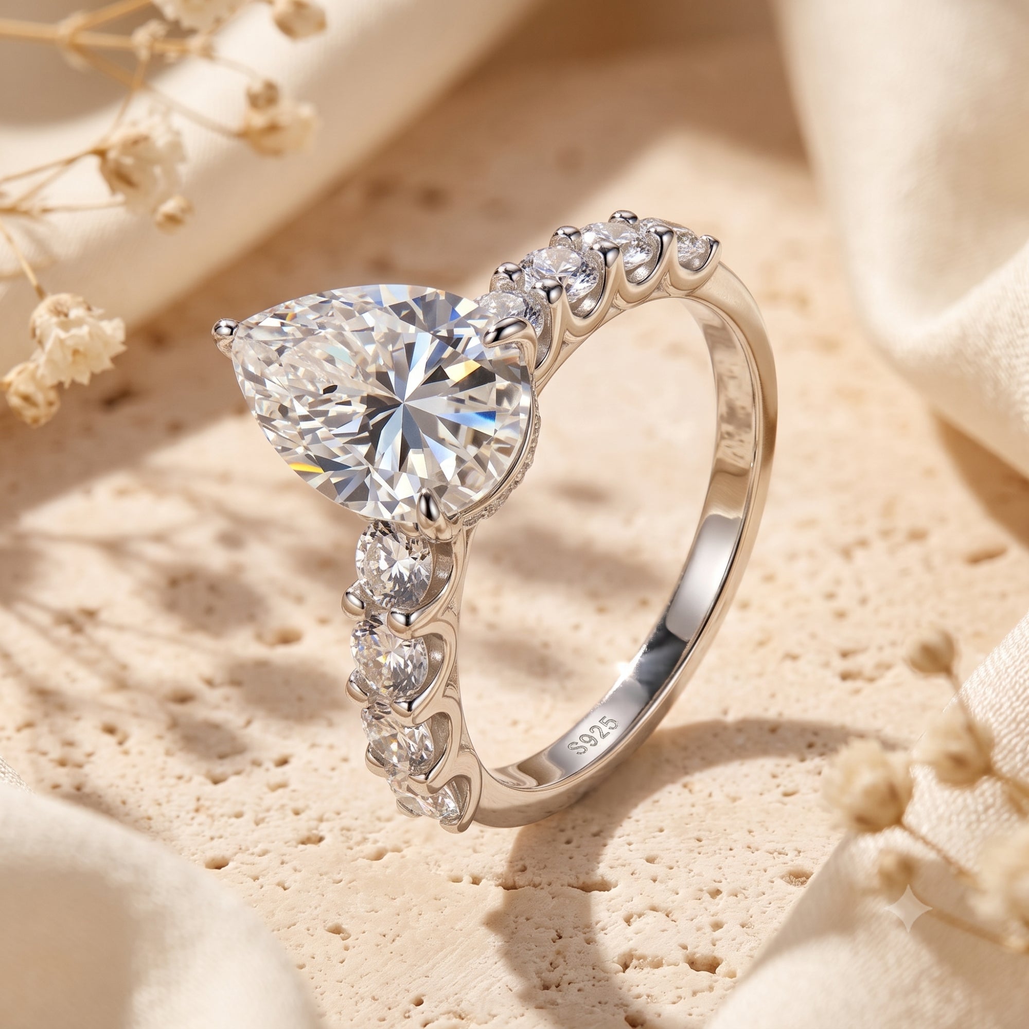 S925 silver pear-cut solitaire ring with accent stones on a lifestyle background.
