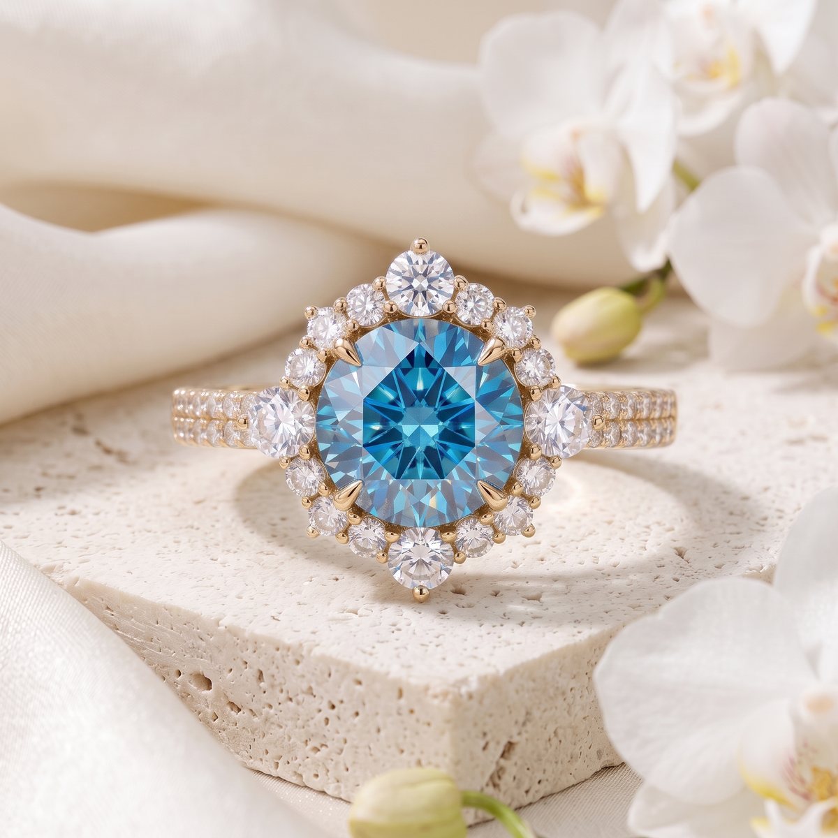 Yellow gold engagement ring with a round blue moissanite center stone and halo on a stone pedestal.