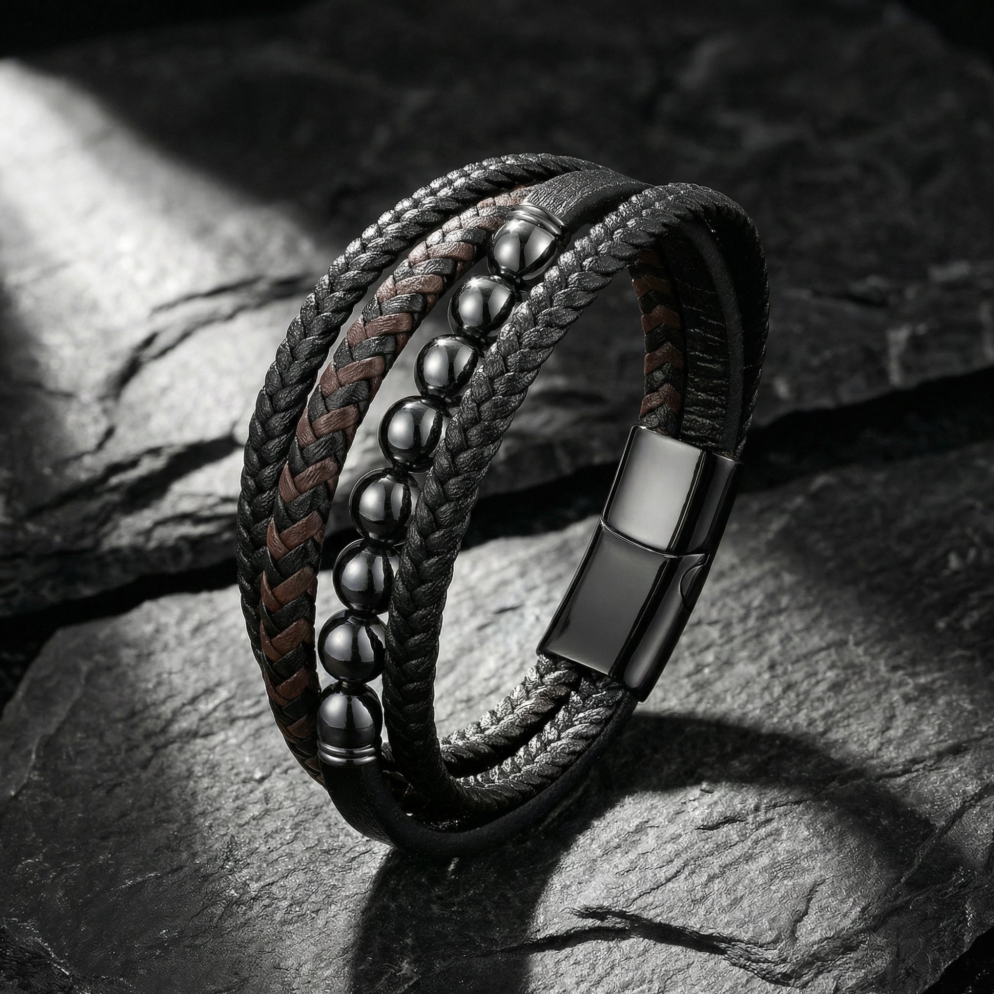 Multi-layer leather bracelet with gunmetal beads and magnetic slide clasp shown on a dark stone background.